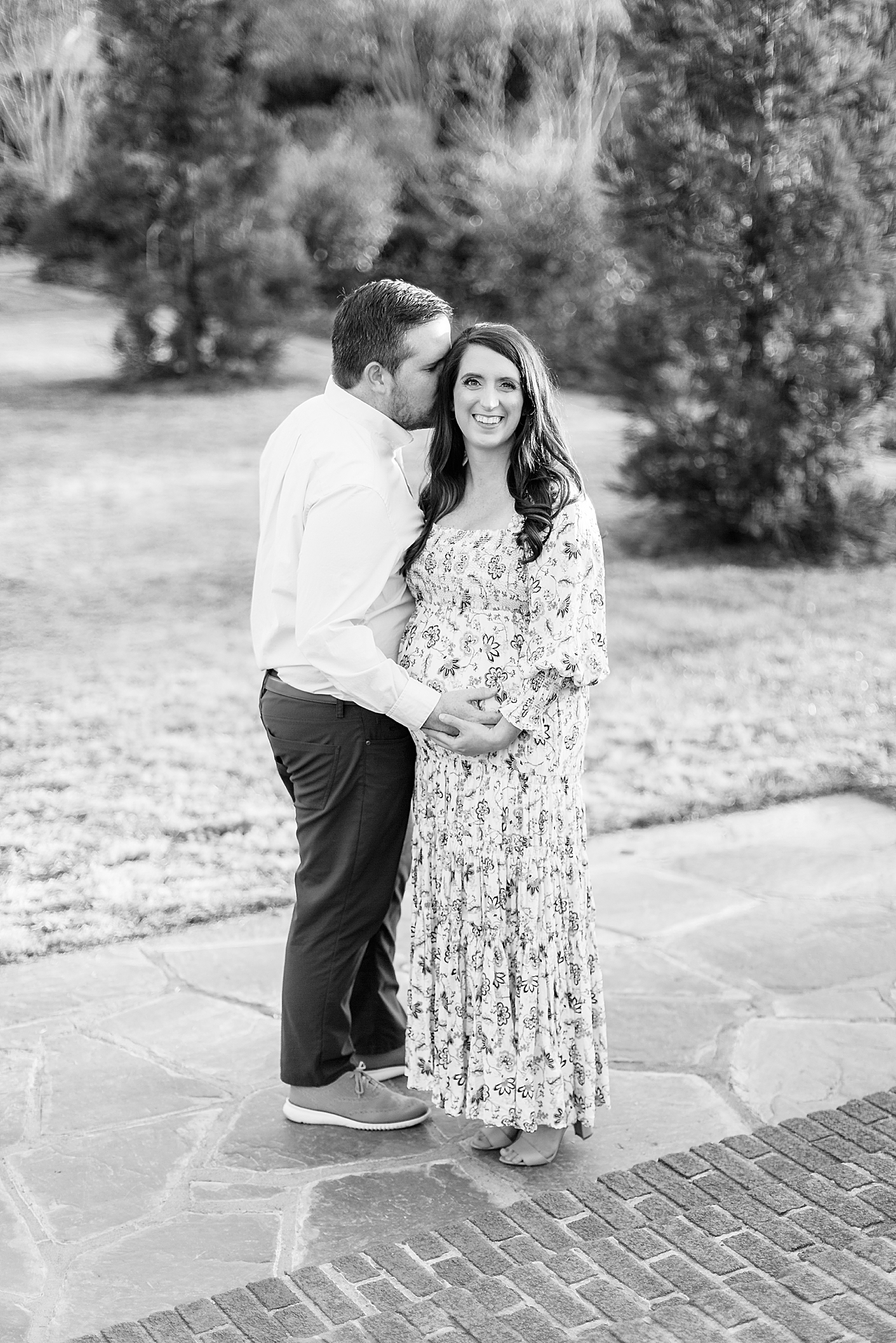 husband kisses wife's forehead while holding belly during Reynolda Village maternity session