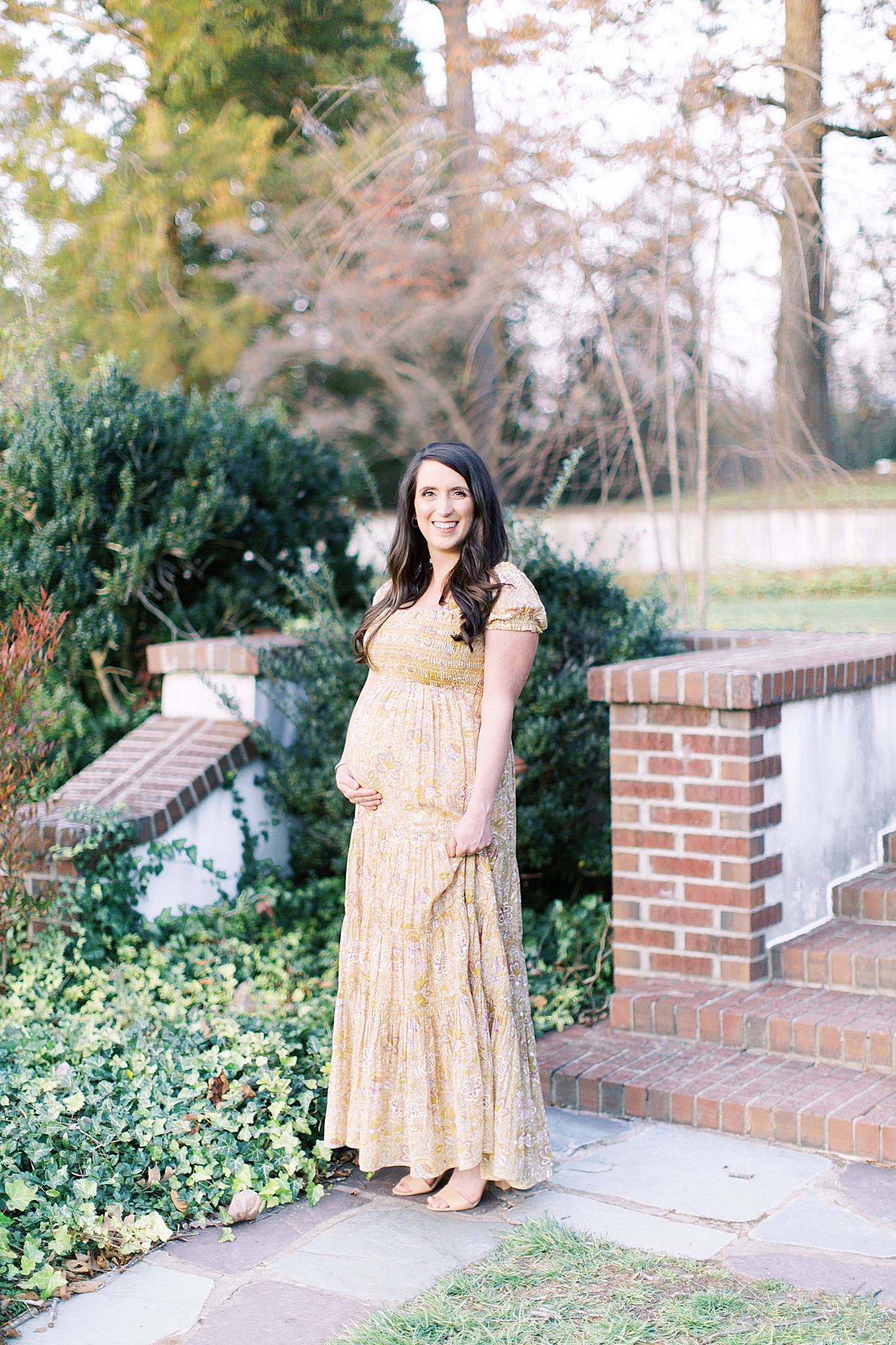 mom holds baby belly and dress during maternity session at Reynolda Village