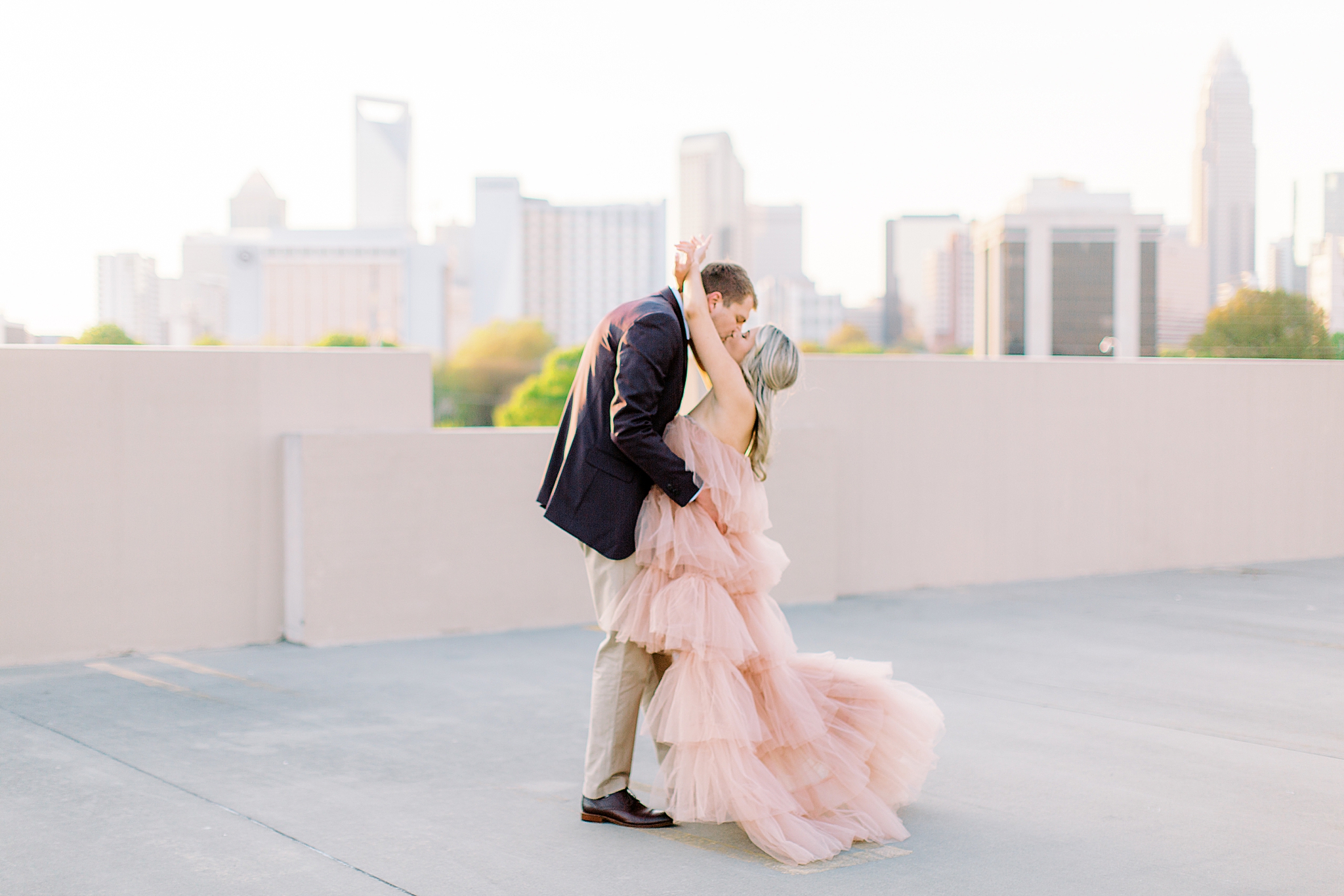 bride and groom stand on rooftop during Charlotte engagement photos