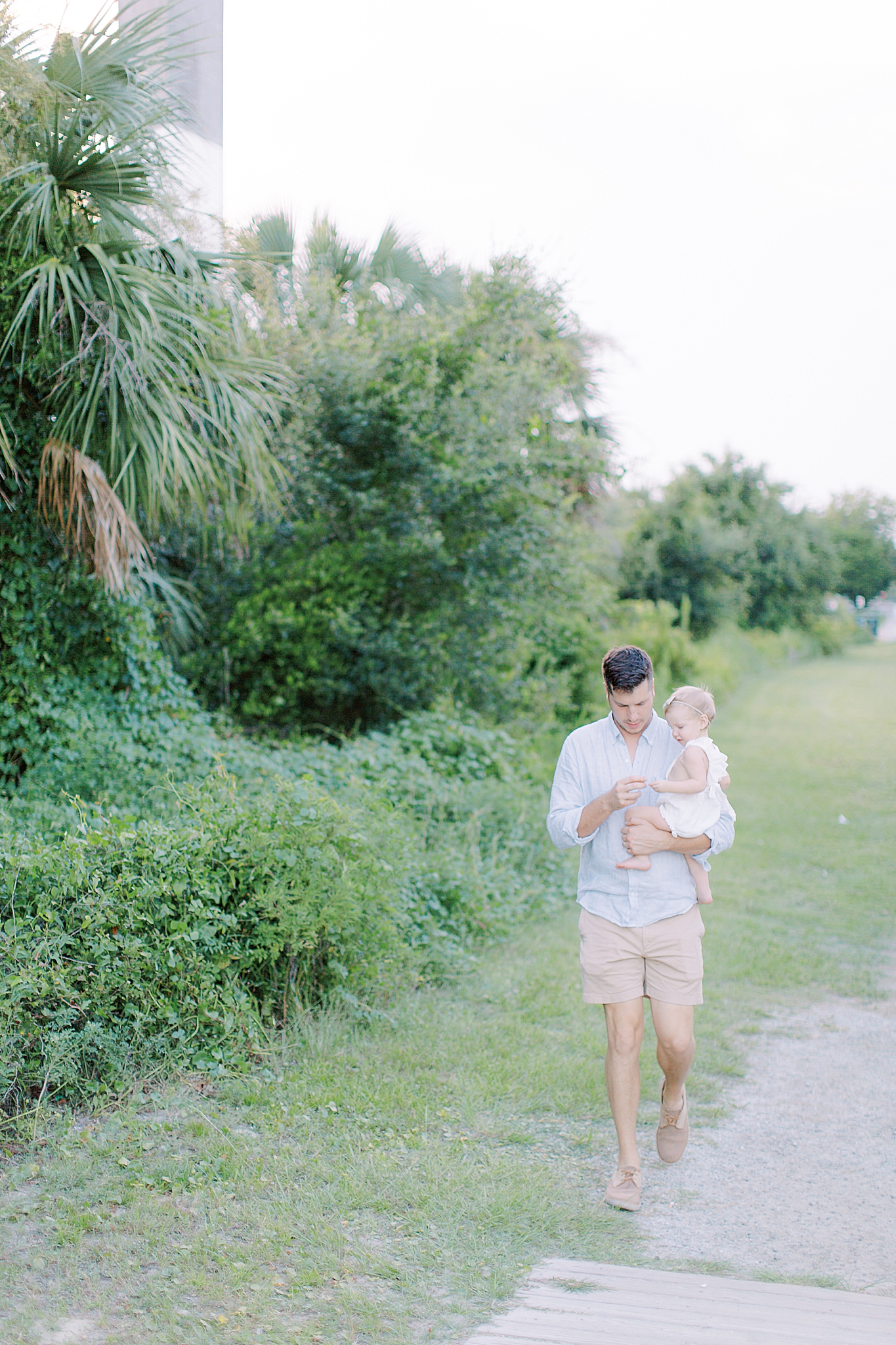 dad and daughter walk along beach in Charleston