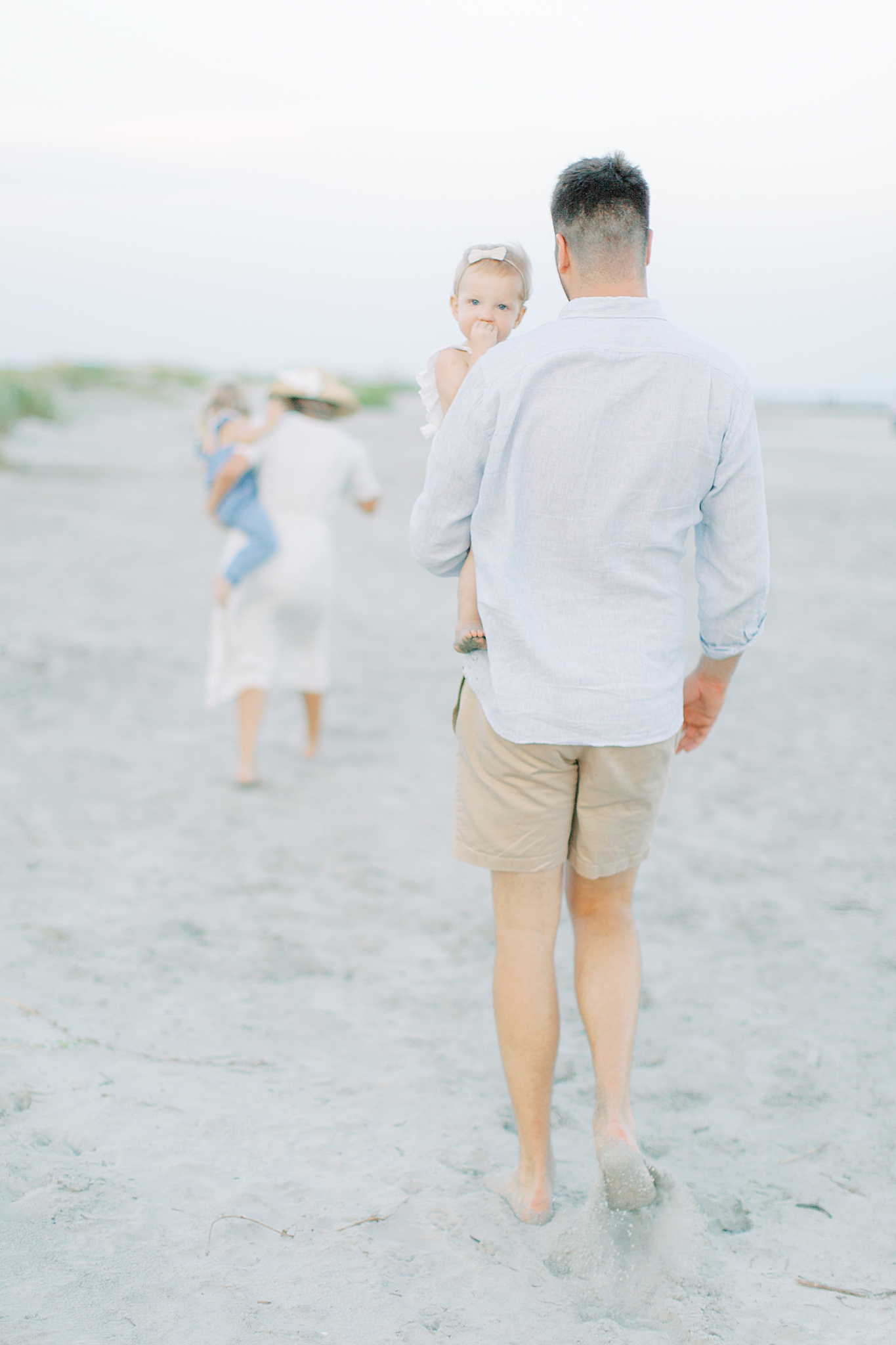 parents carry girls through sand during Sullivans Island family session
