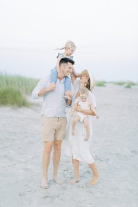 parents pose with two girls on beach in Charleston