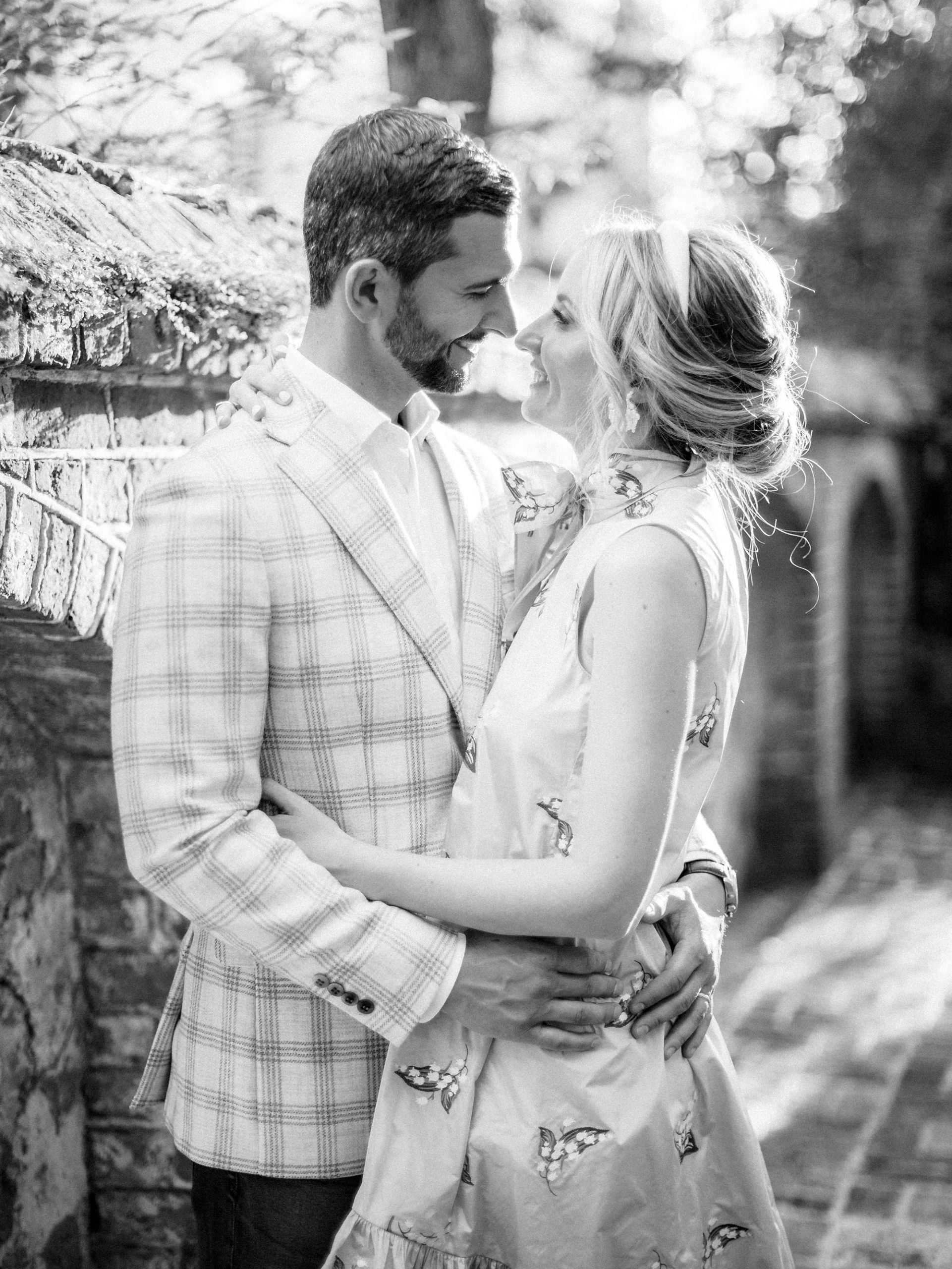married couple hugs on street with brick wall