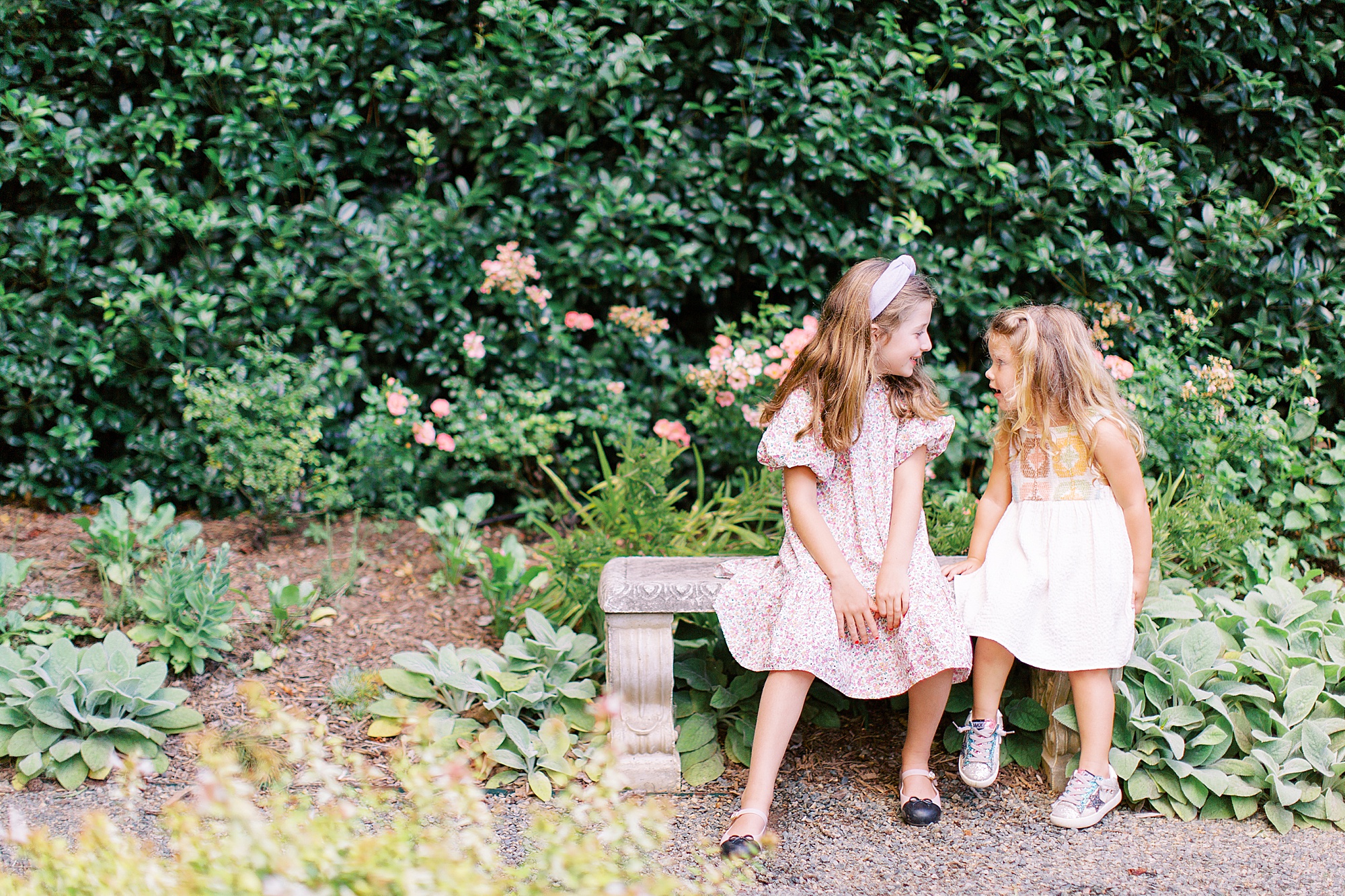sisters sit on garden bench together in Charlotte NC