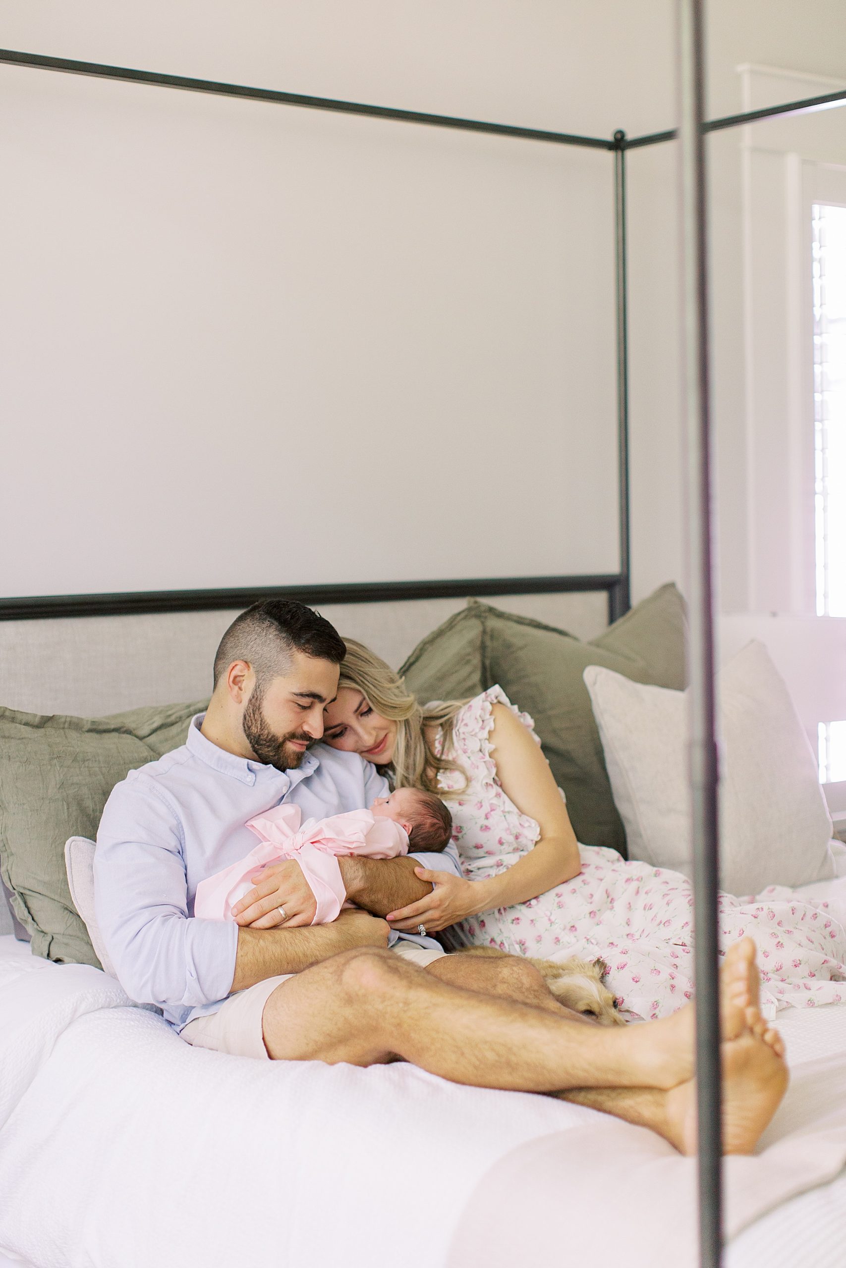 parents lay together in bed looking at new baby girl