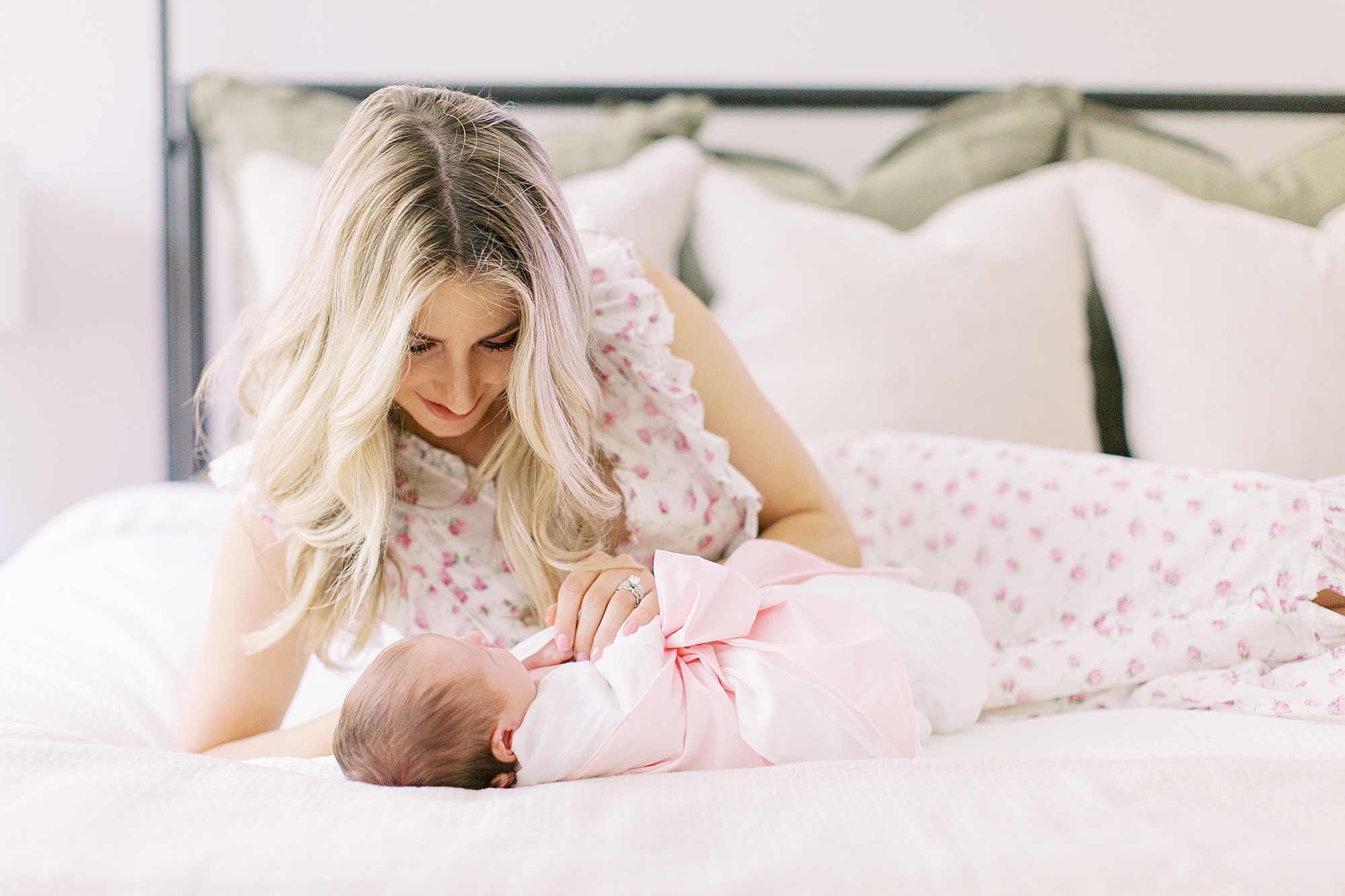 mom looks down at baby girl on bed during Charlotte NC newborn photos