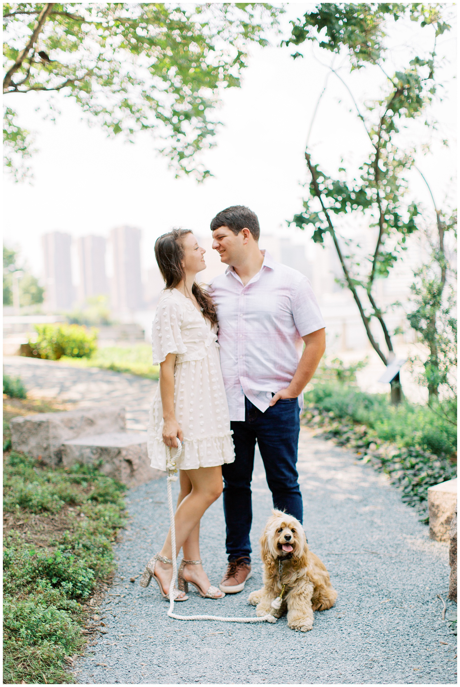 bride and groom pose with dog on walkway in New York City during engagement photos 