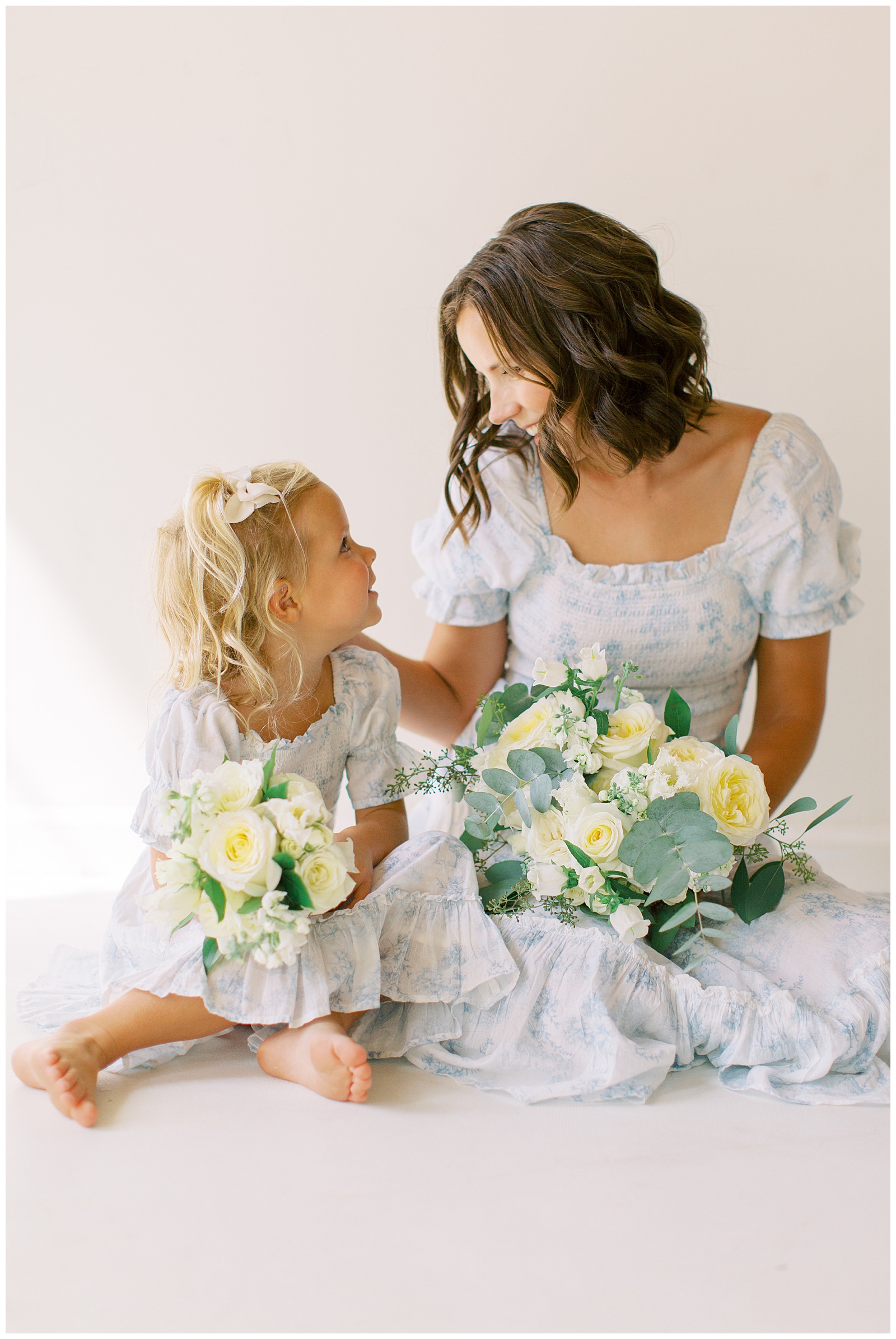 mom looks at daughter in matching blue and white gown during branding photos