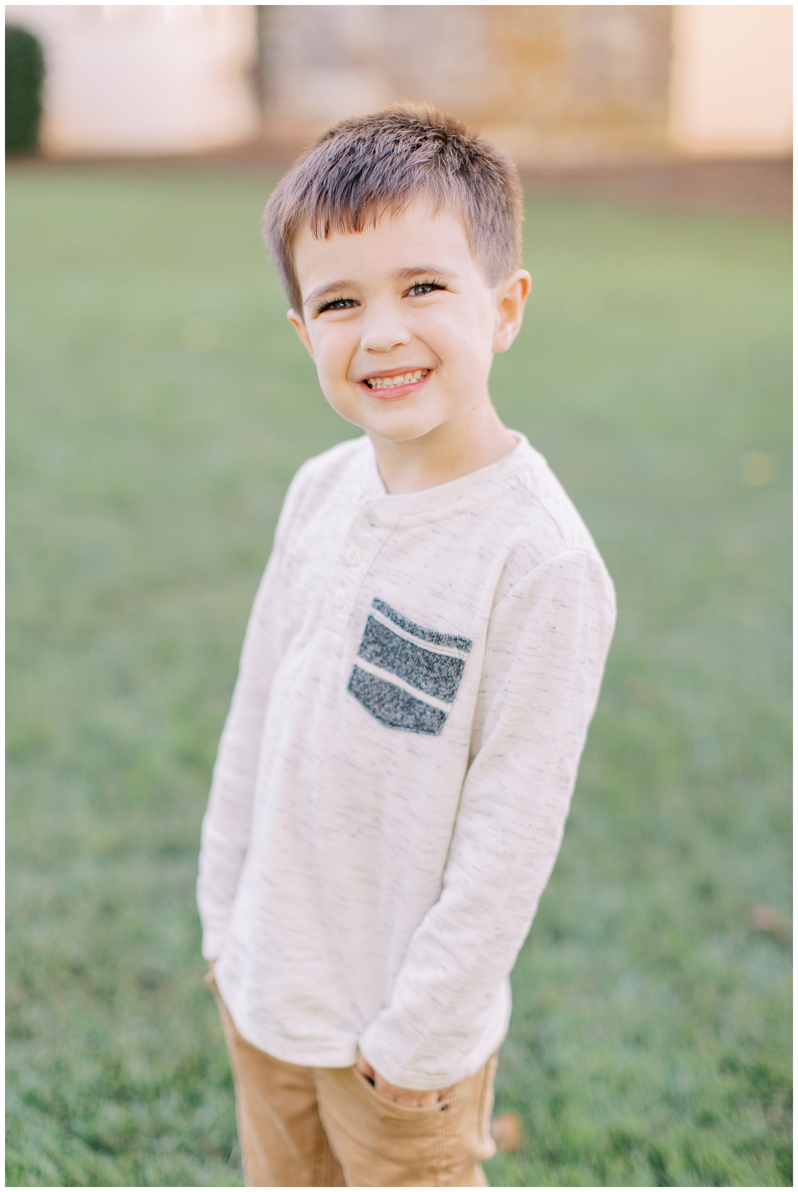 young boy stands with hands in pockets smiling during NC family photos