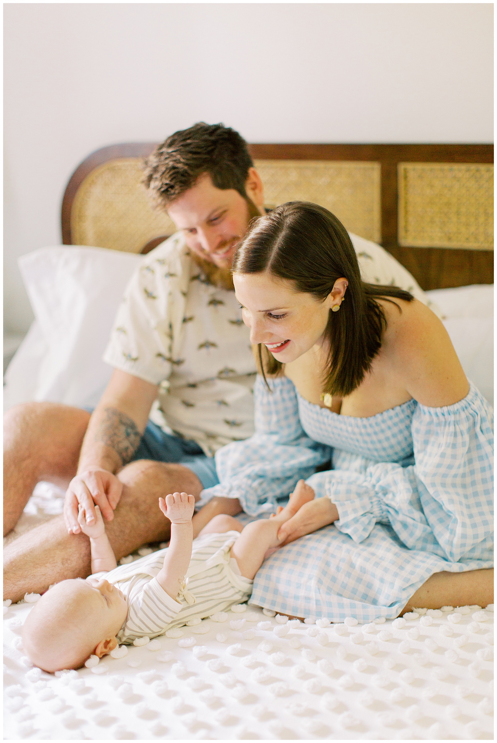 new parents smile at baby boy on bed during lifestyle newborn session in Charlotte home