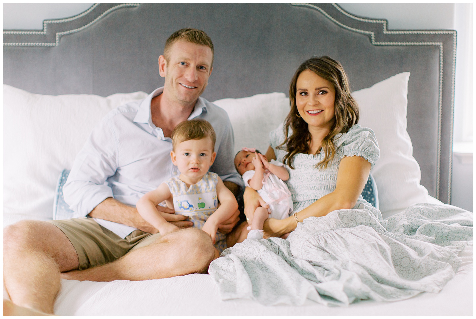 family of four sits on bed during Lifestyle Newborn Session in Charlotte