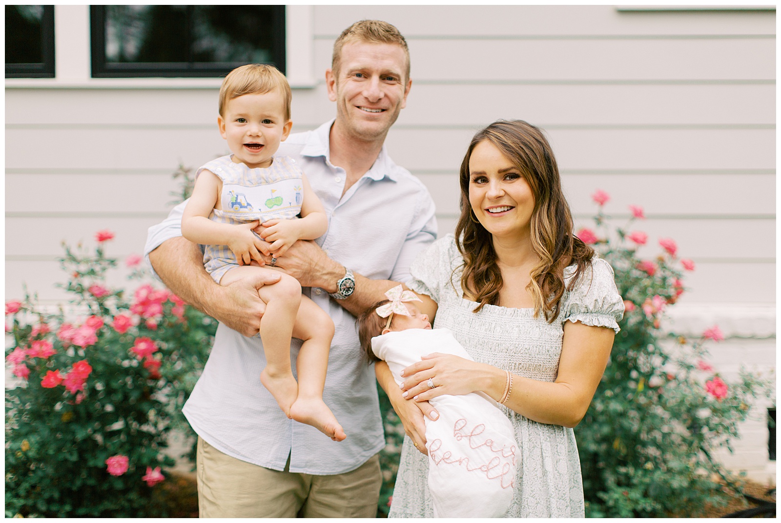 family of four poses in garden during Lifestyle Newborn Session in Charlotte