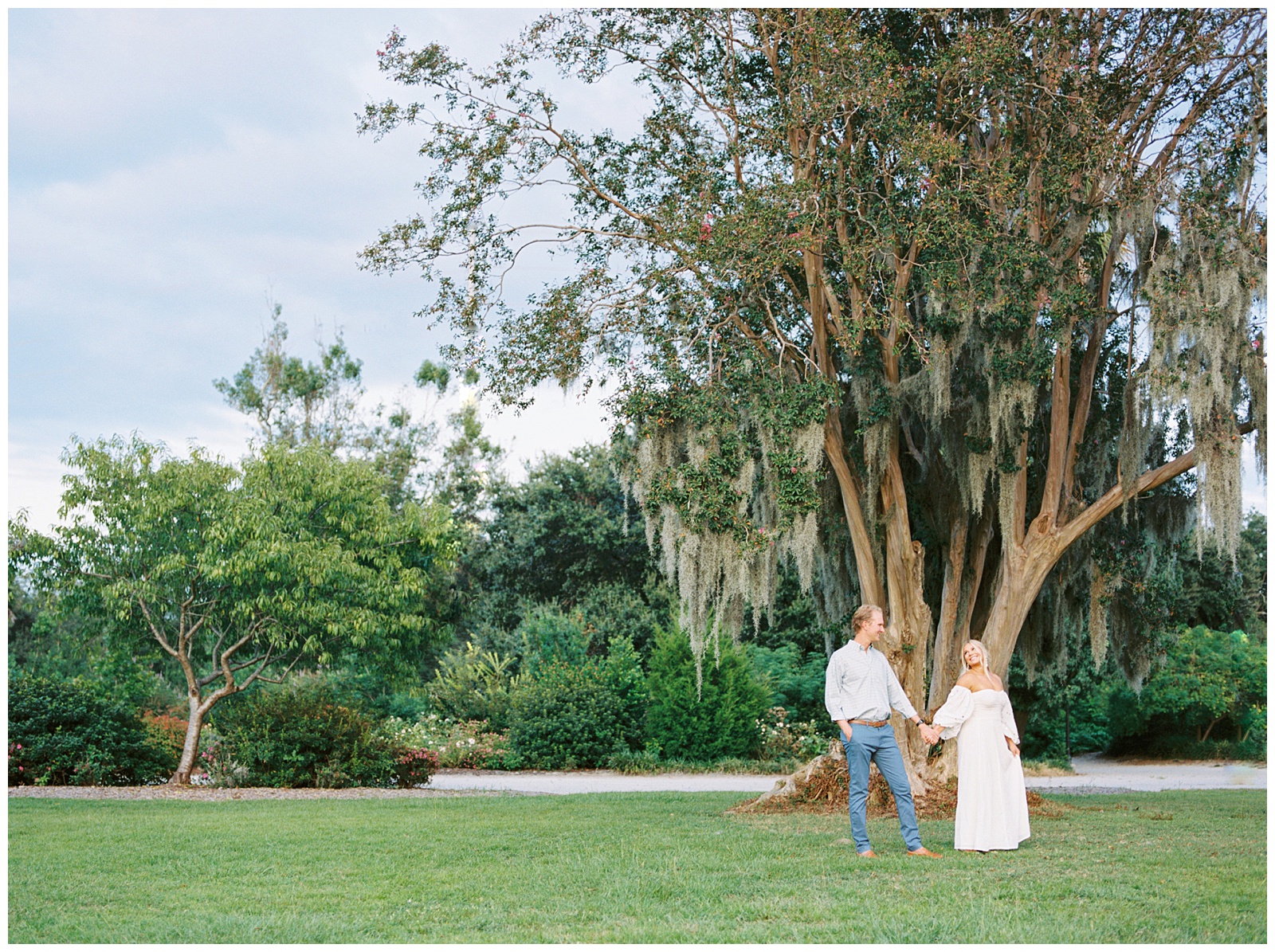bride and groom walk by tree with Spanish Moss in Hampton Park 