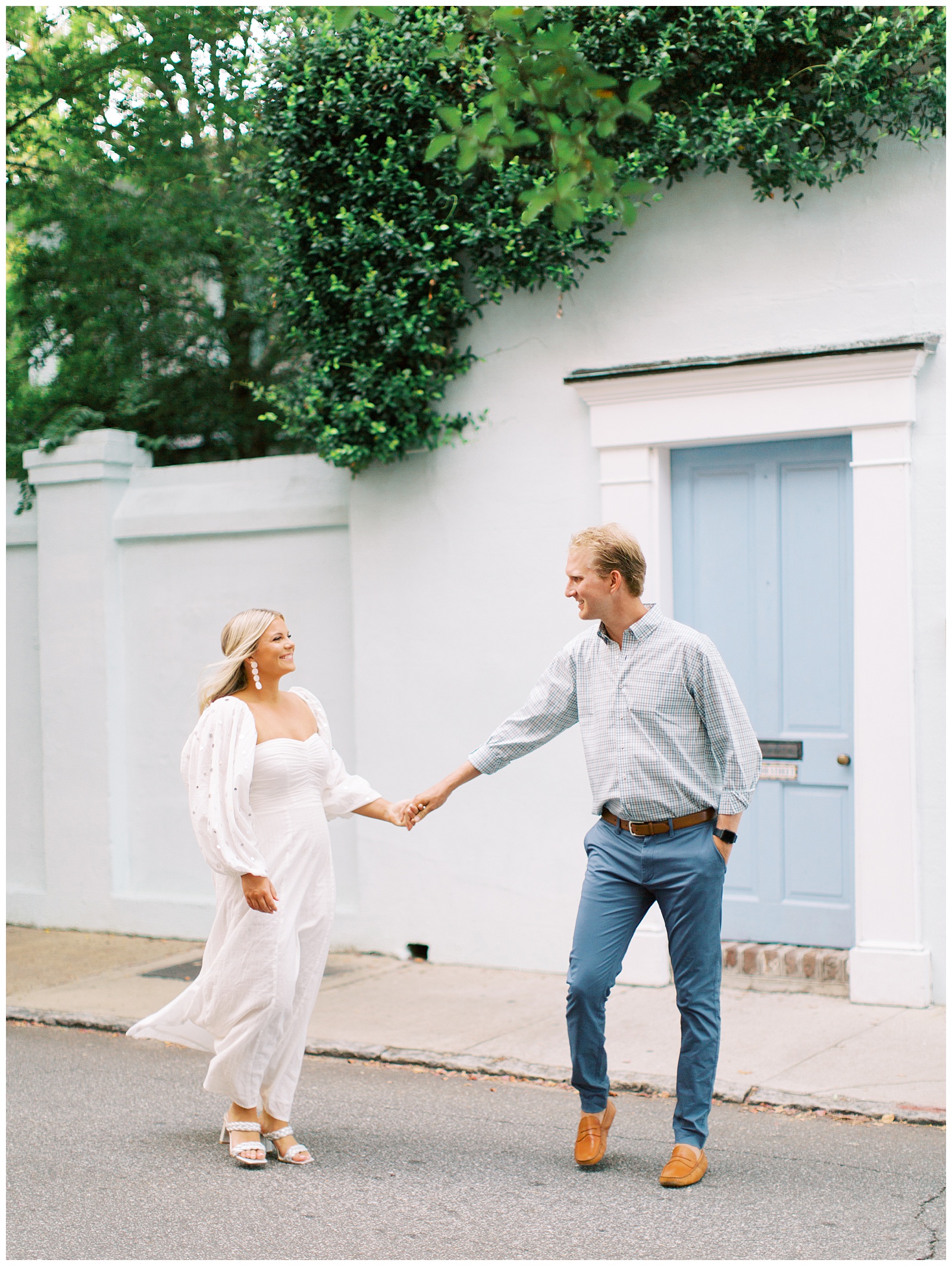 bride and groom hold hands walking by historic homes in Charleston SC
