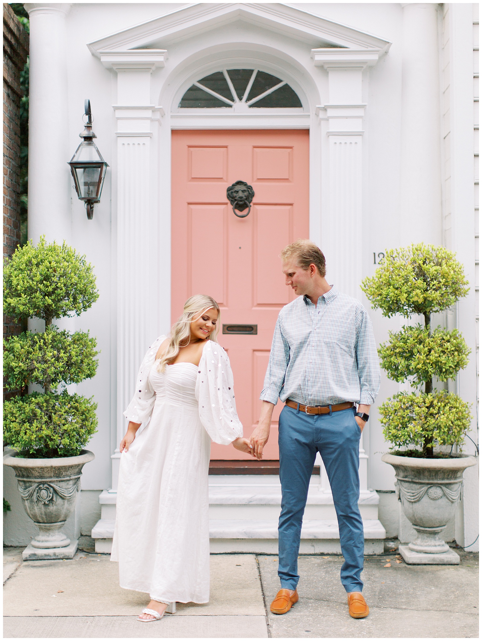 bride and groom hold hands by pink door in Charleston SC