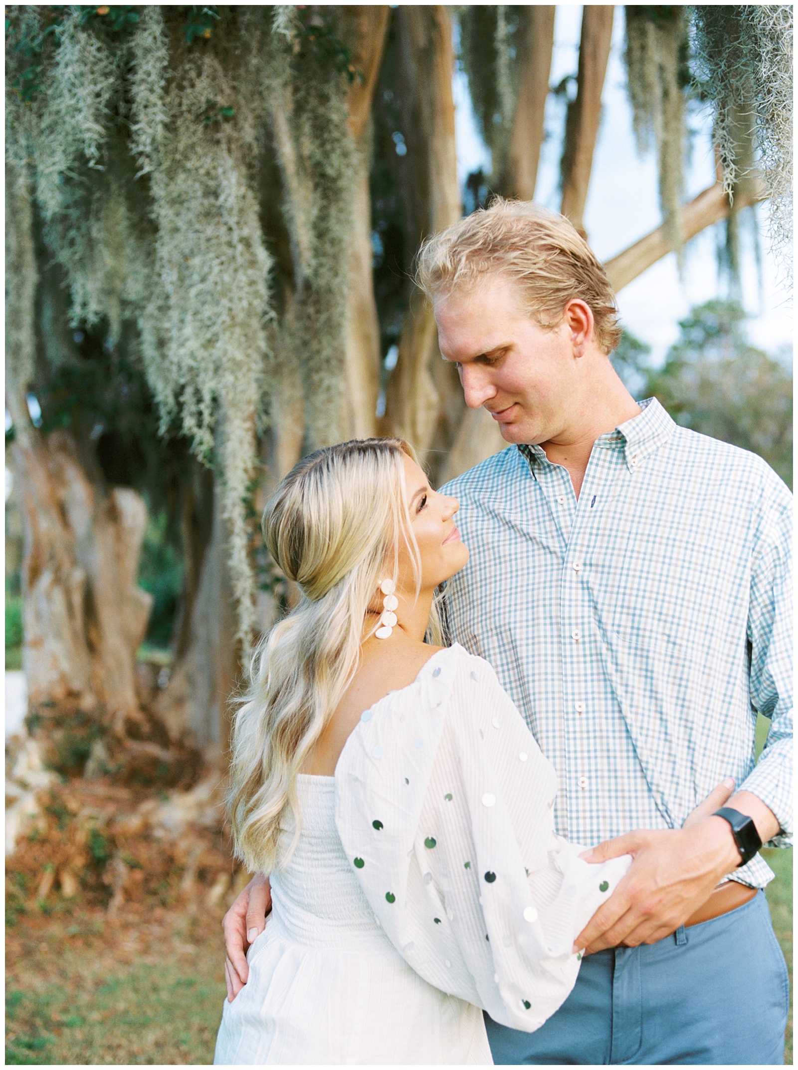 bride and groom smile at each other by trees with Spanish Moss in Hampton Park 