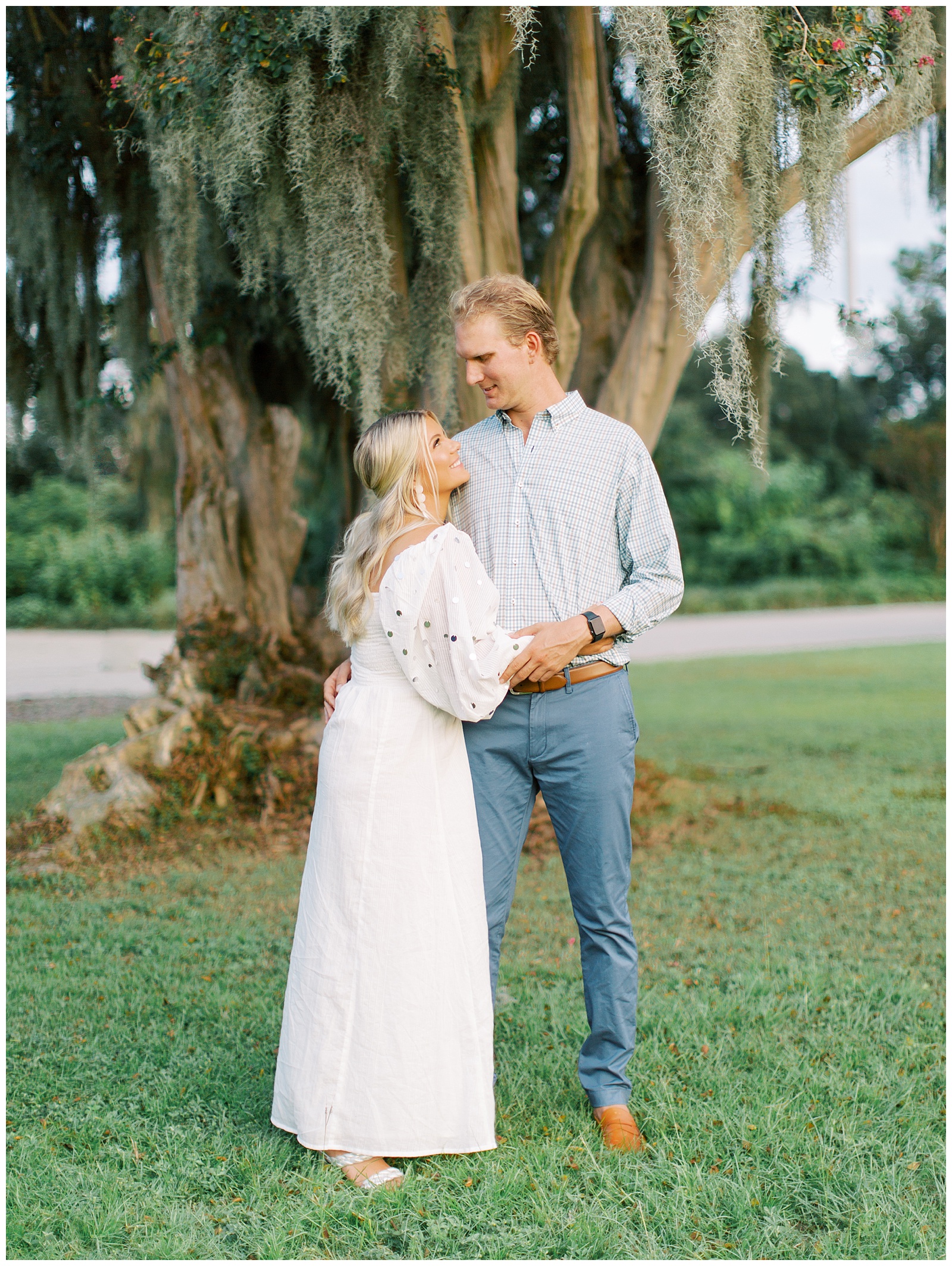 couple hugs by tree with Spanish moss in Hampton Park