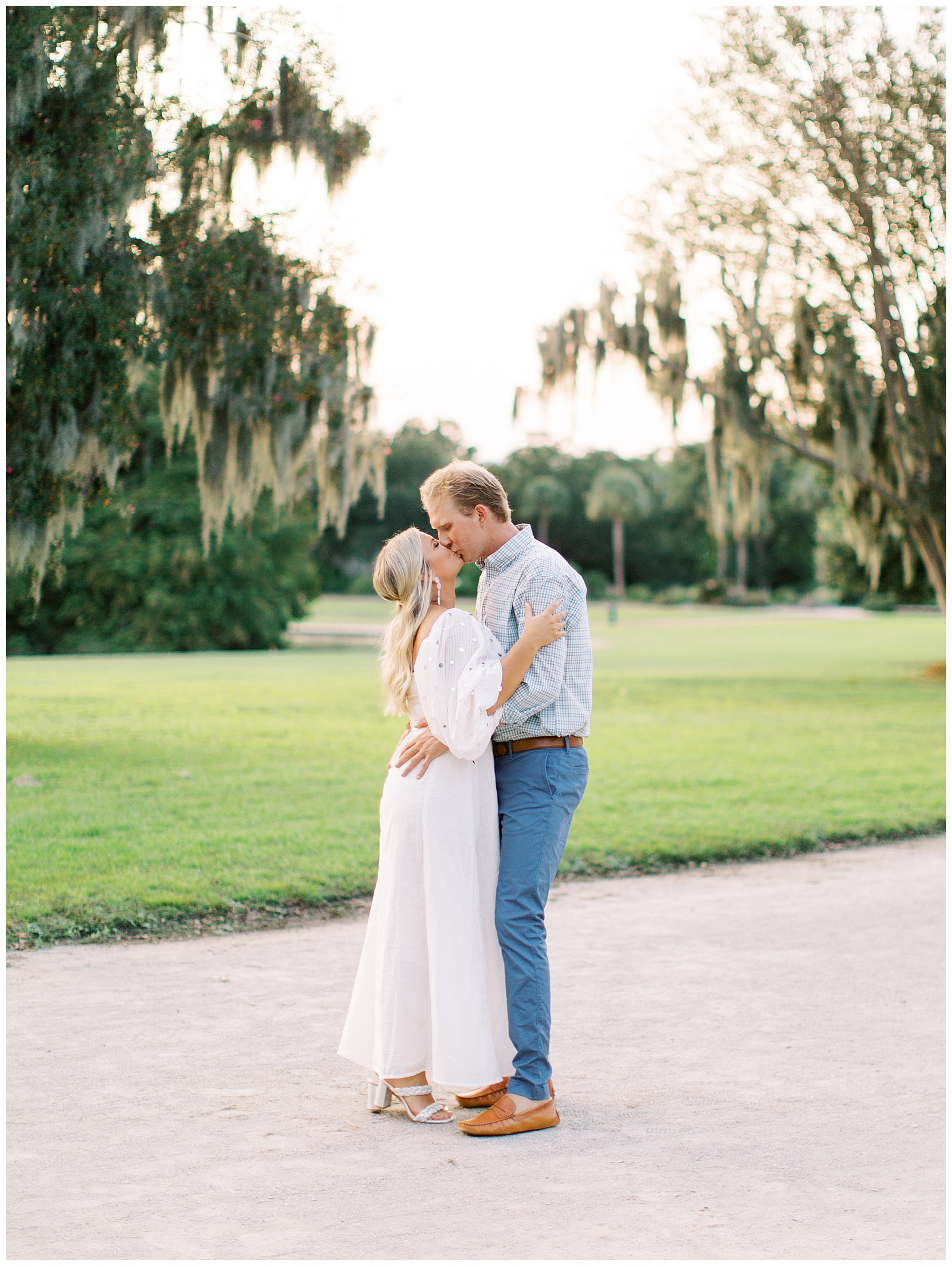 engaged couple kiss at sunset in Hampton Park by Spanish moss