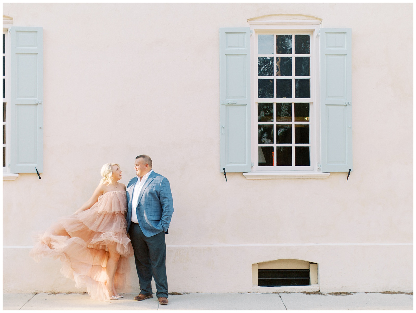 bride moves skirt for pink statement dress during Downtown Charleston engagement session