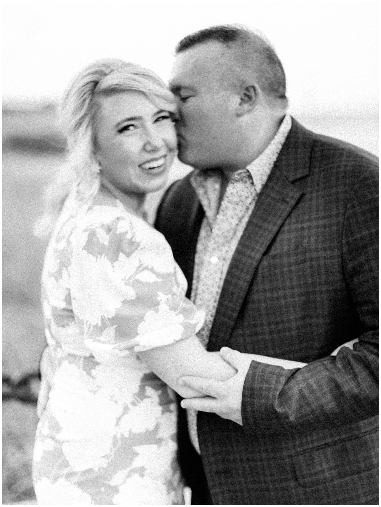 groom kisses bride's cheek during Downtown Charleston engagement session