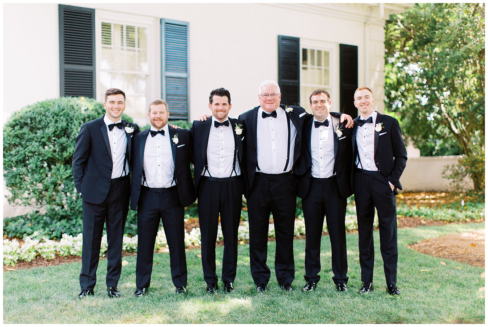 groom poses with groomsmen in classic black tuxes