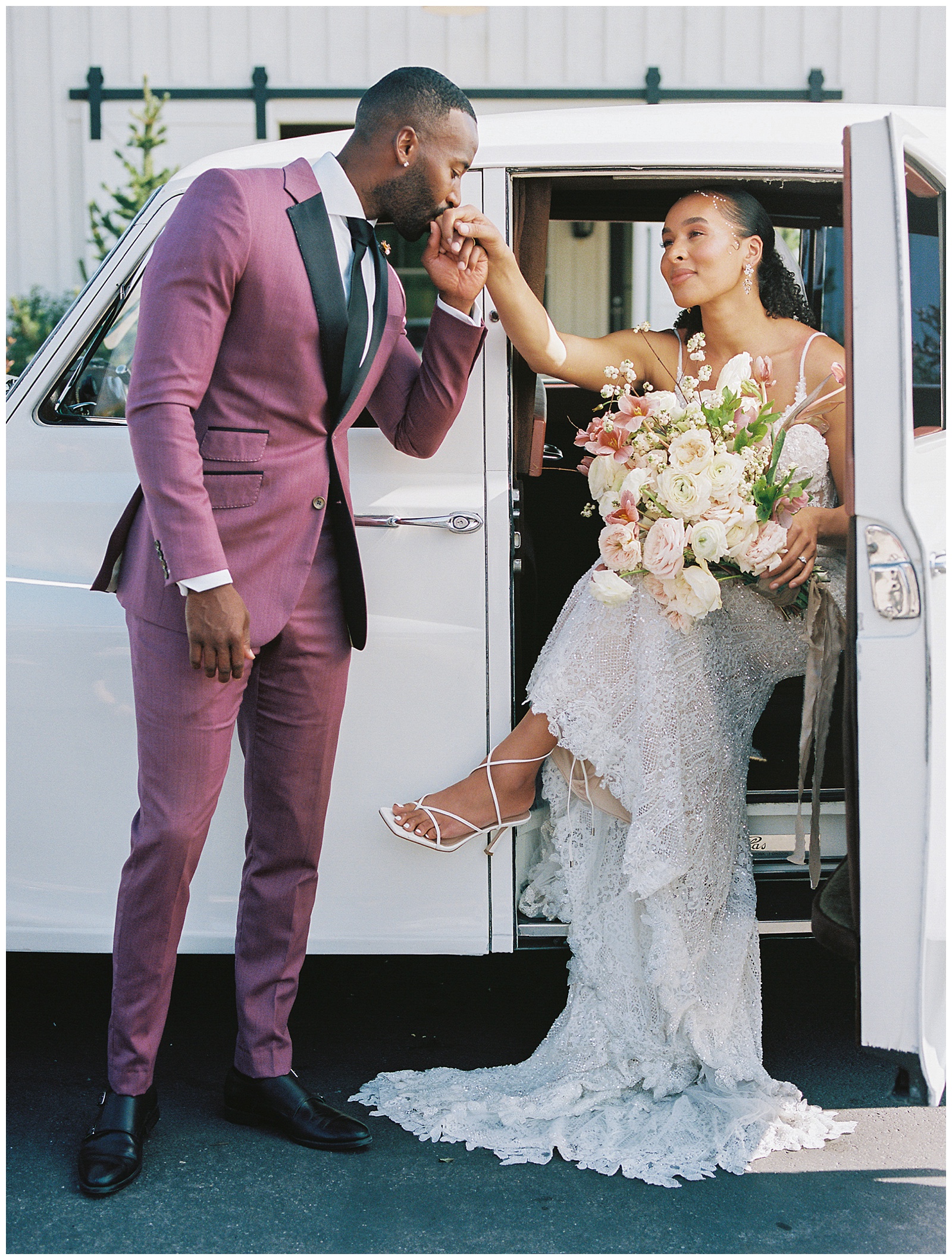 groom kisses bride's hand as he helps her out of Rolls Royce