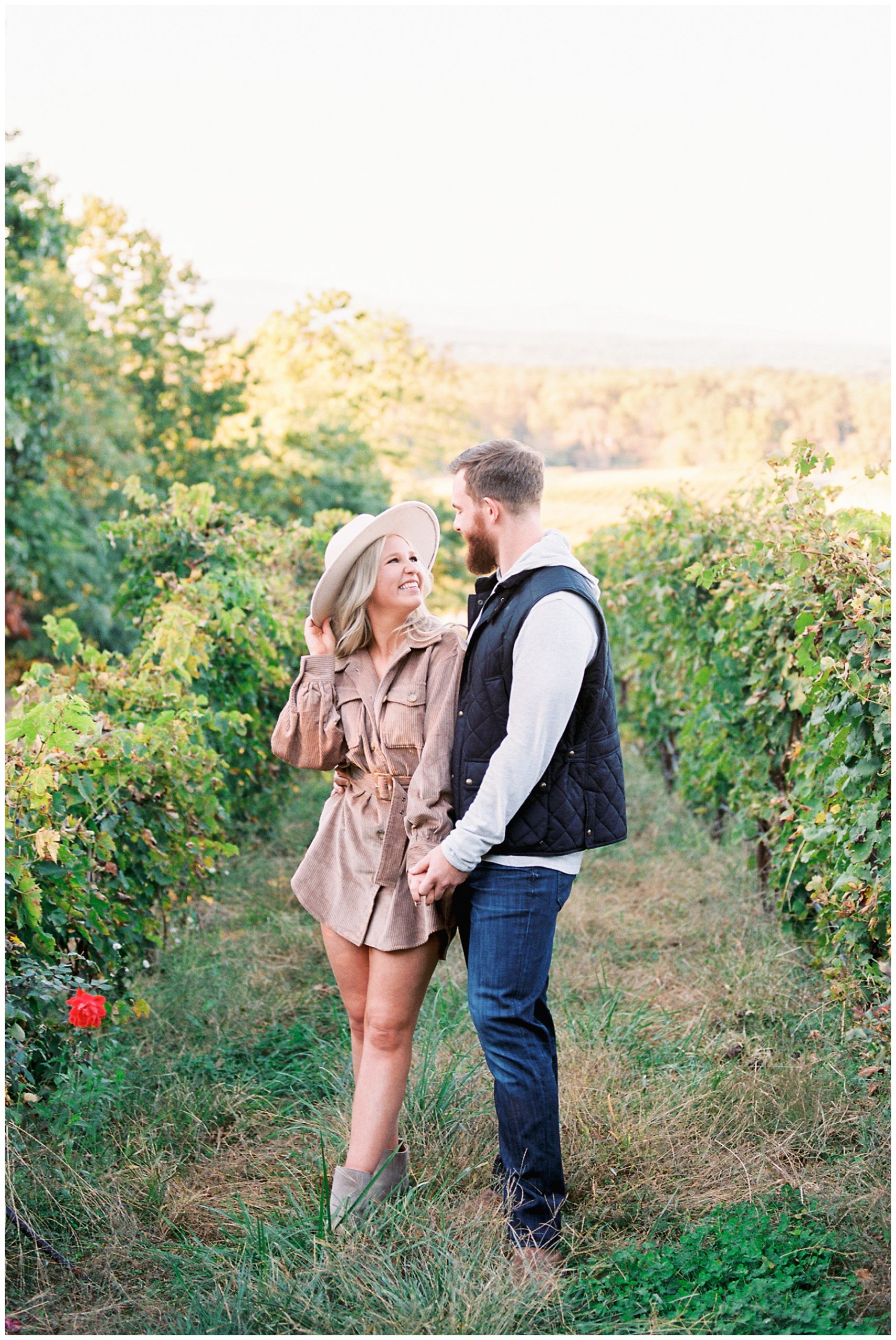 engaged couple holds hands walking through vines at Raffaldini Vineyards