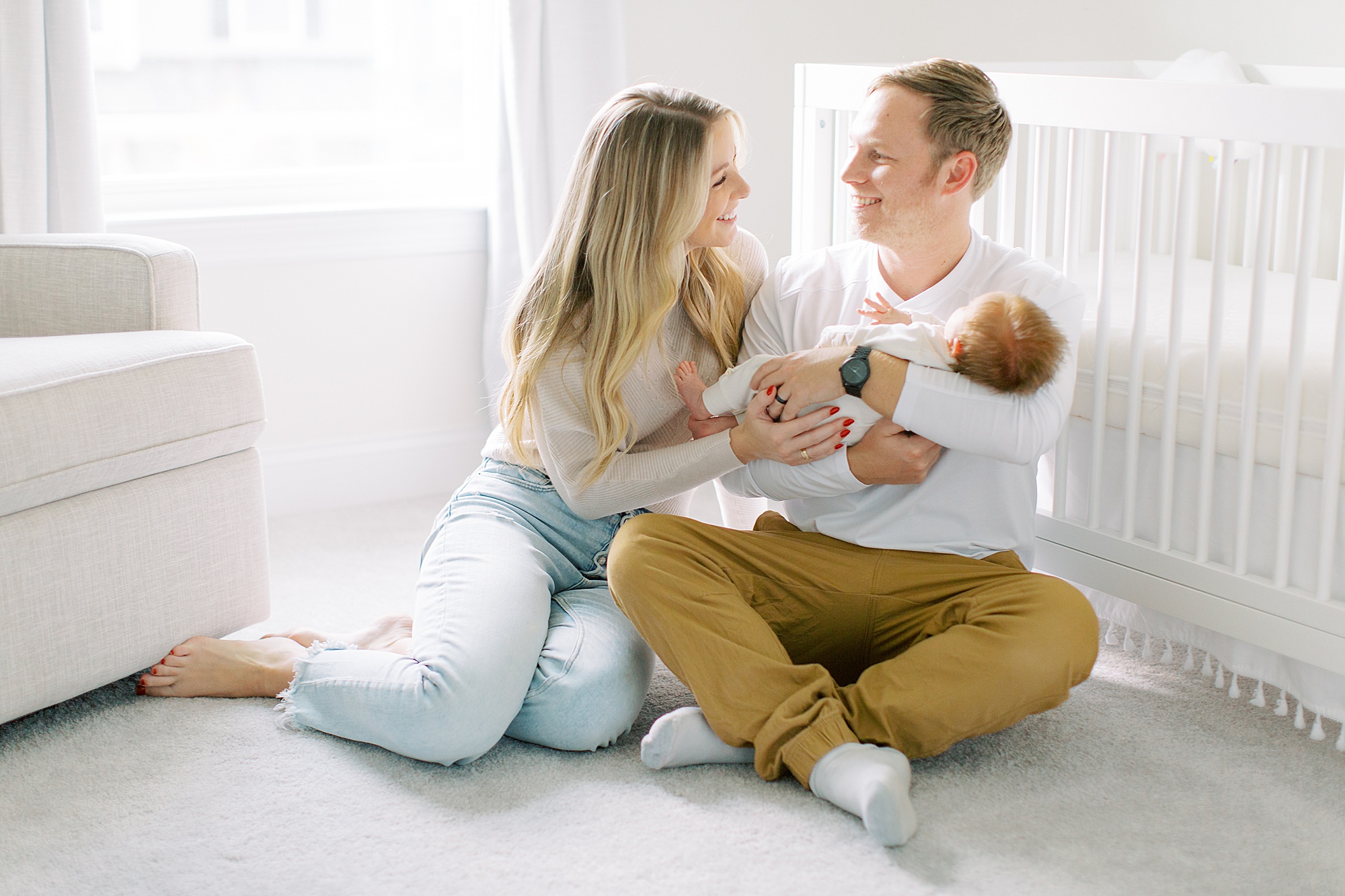 new parents laugh together holding baby during Charlotte newborn session