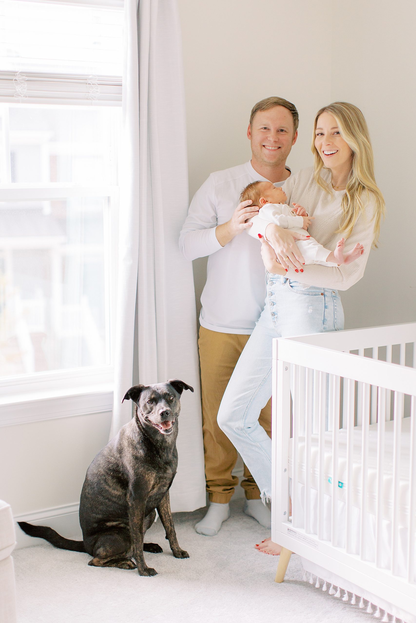 parnets pose with dog and crib during lifestyle newborn session