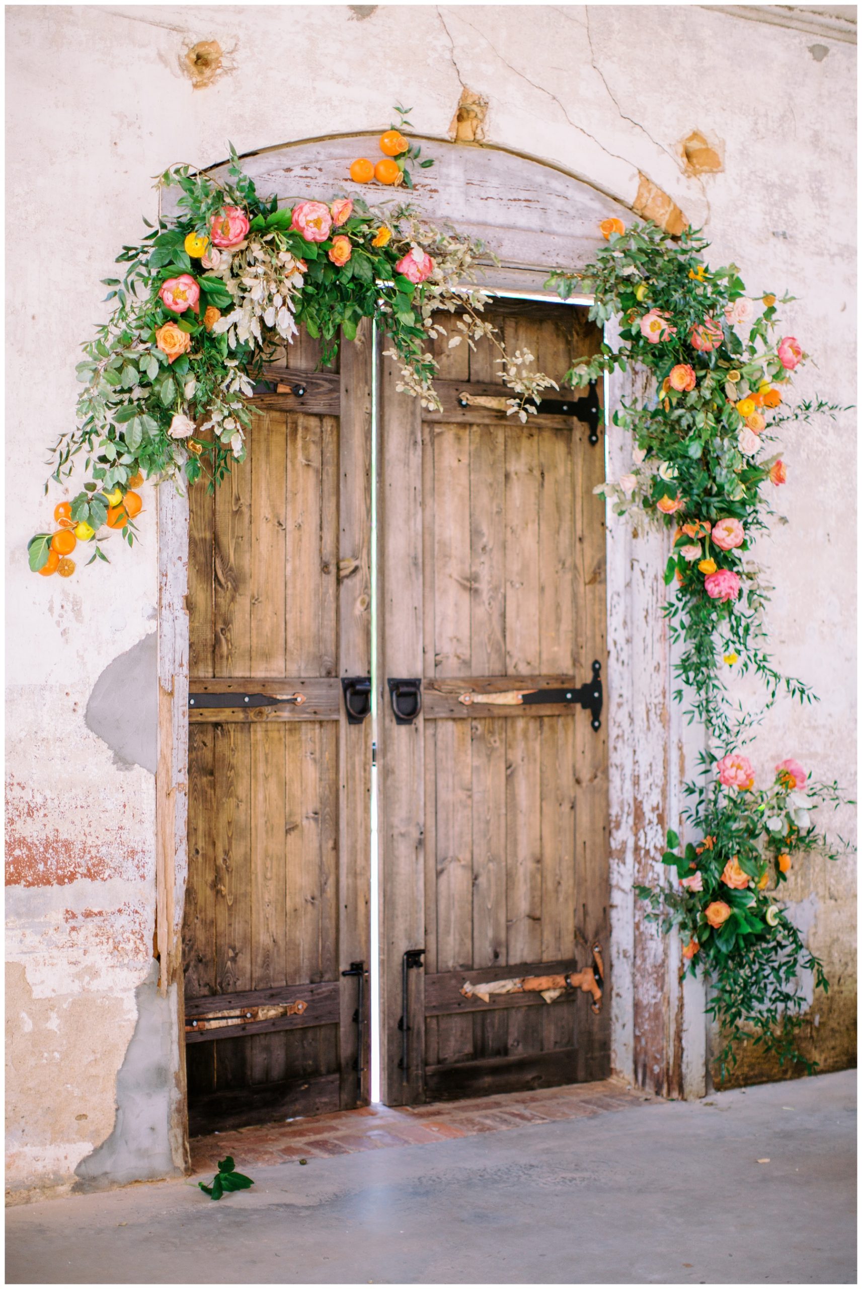 floral displays with orange and pink flowers around wooden door at Providence Cotton Mill 