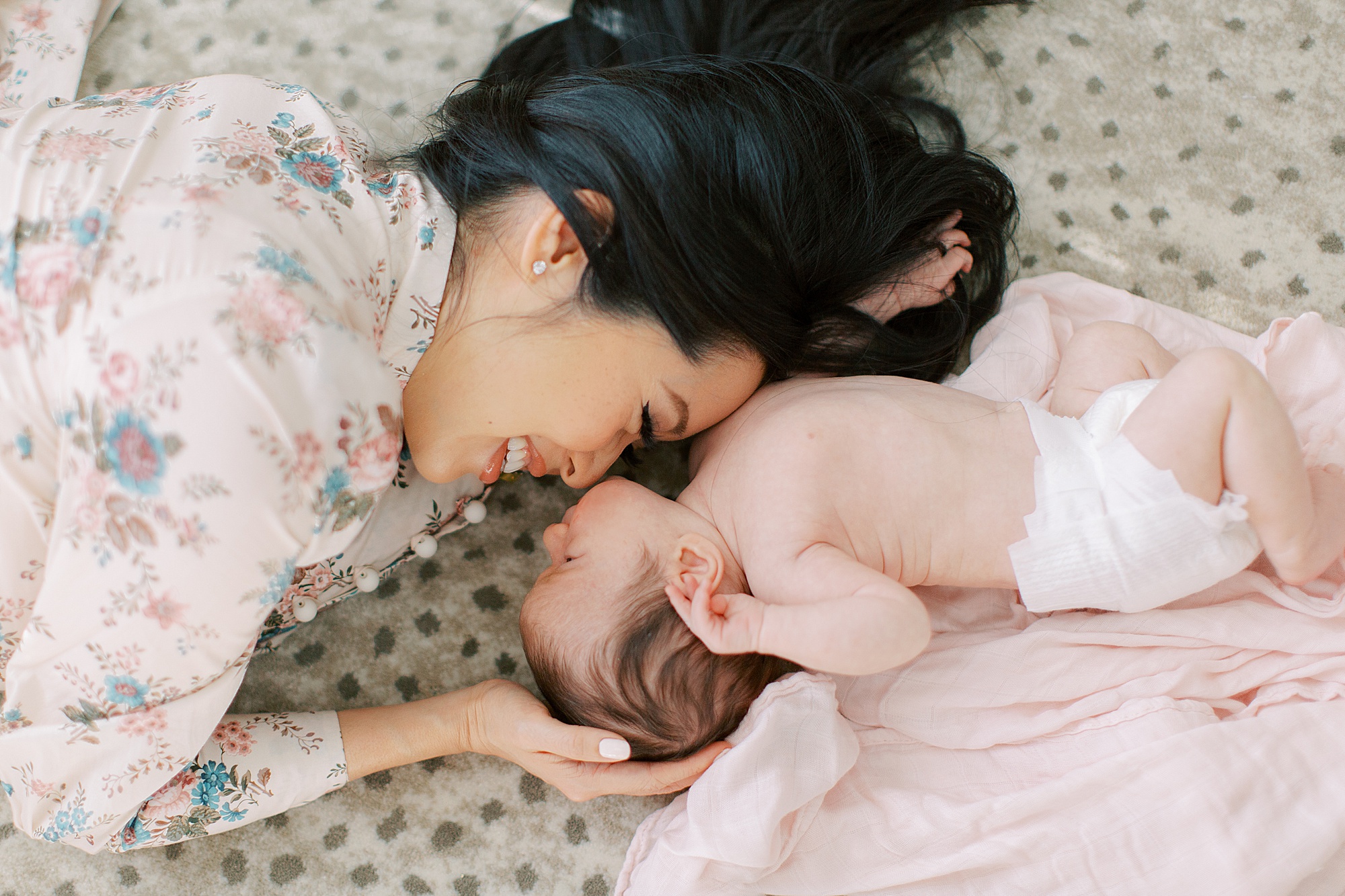 mom nuzzles baby's nose on rug during at-home newborn portraits