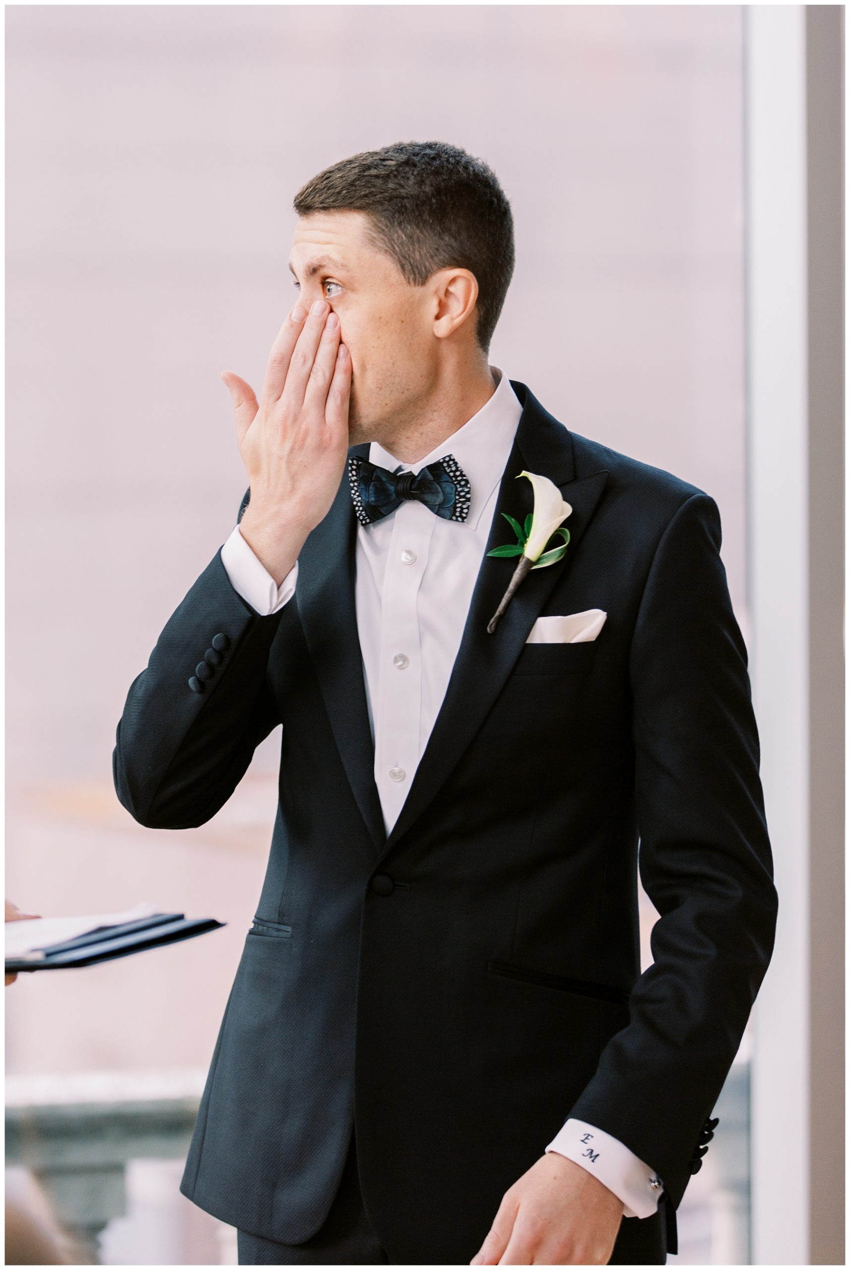 groom wipes away tears during wedding ceremony