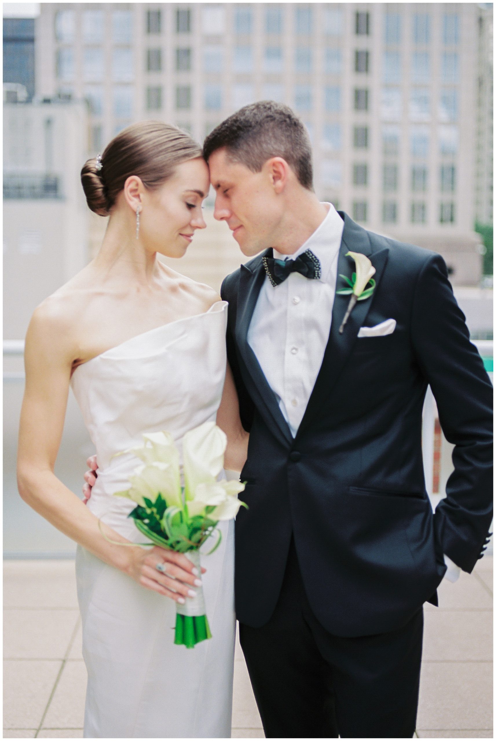 bride holding calla lilies touches foreheads with groom during portraits in Charlotte NC