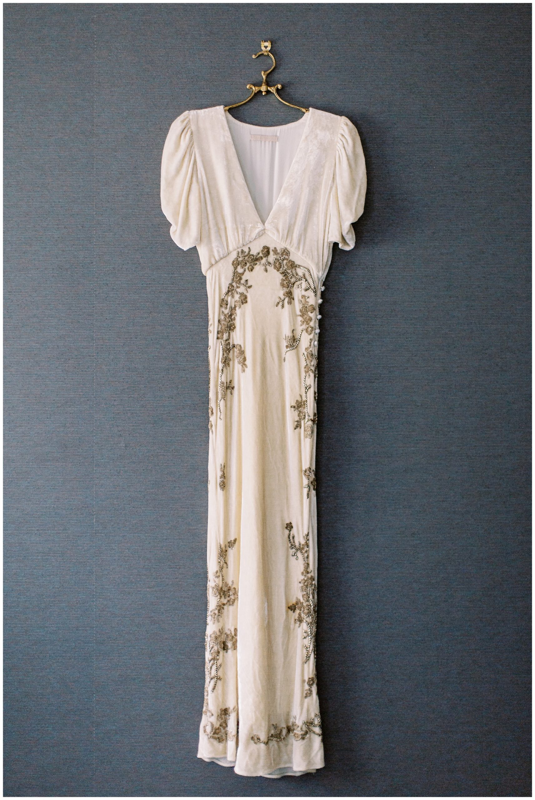 vintage ivory and gold wedding gown hanging on wall