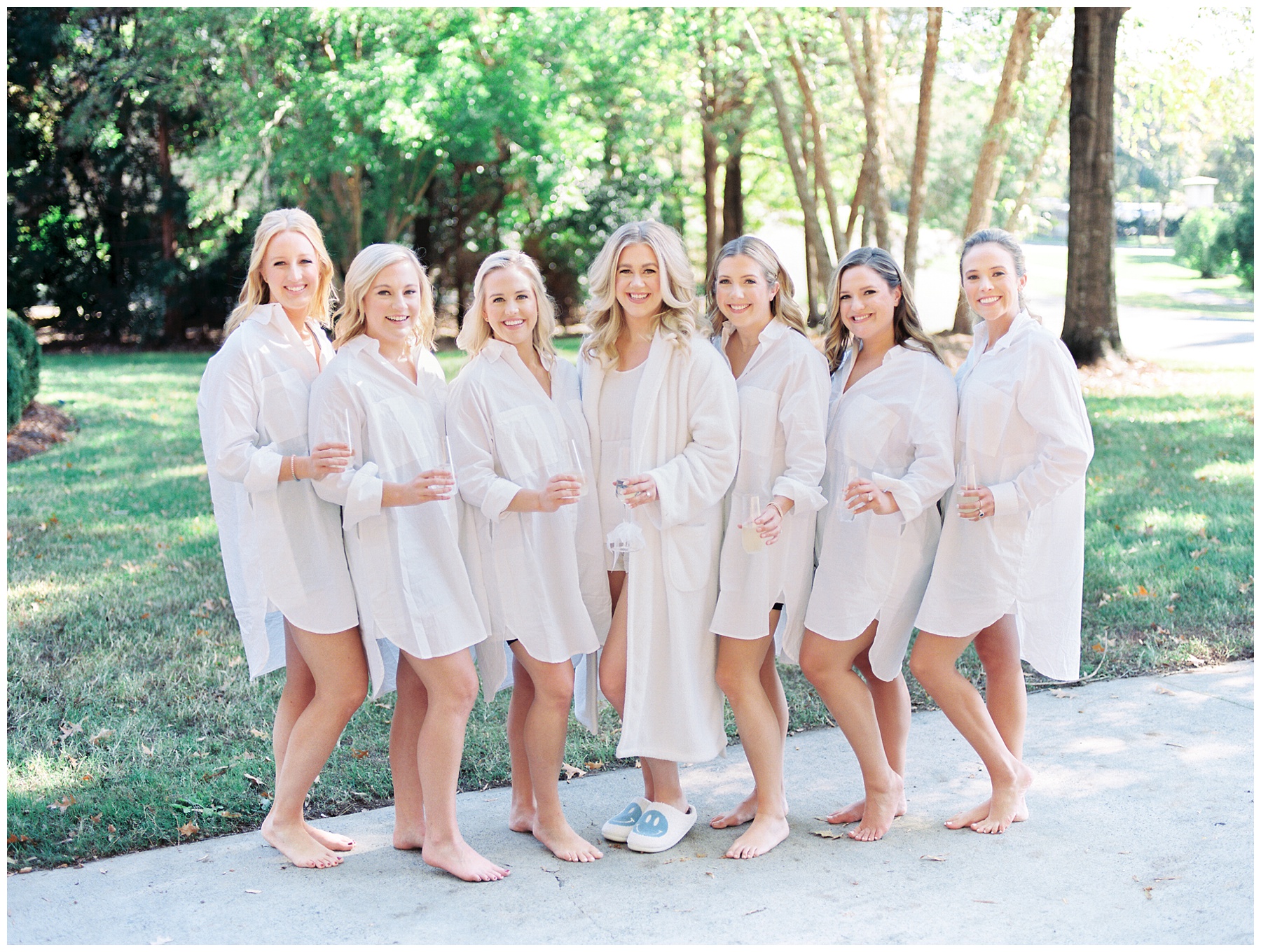 bride poses with bridesmaids in robes in Charlotte NC on wedding morning