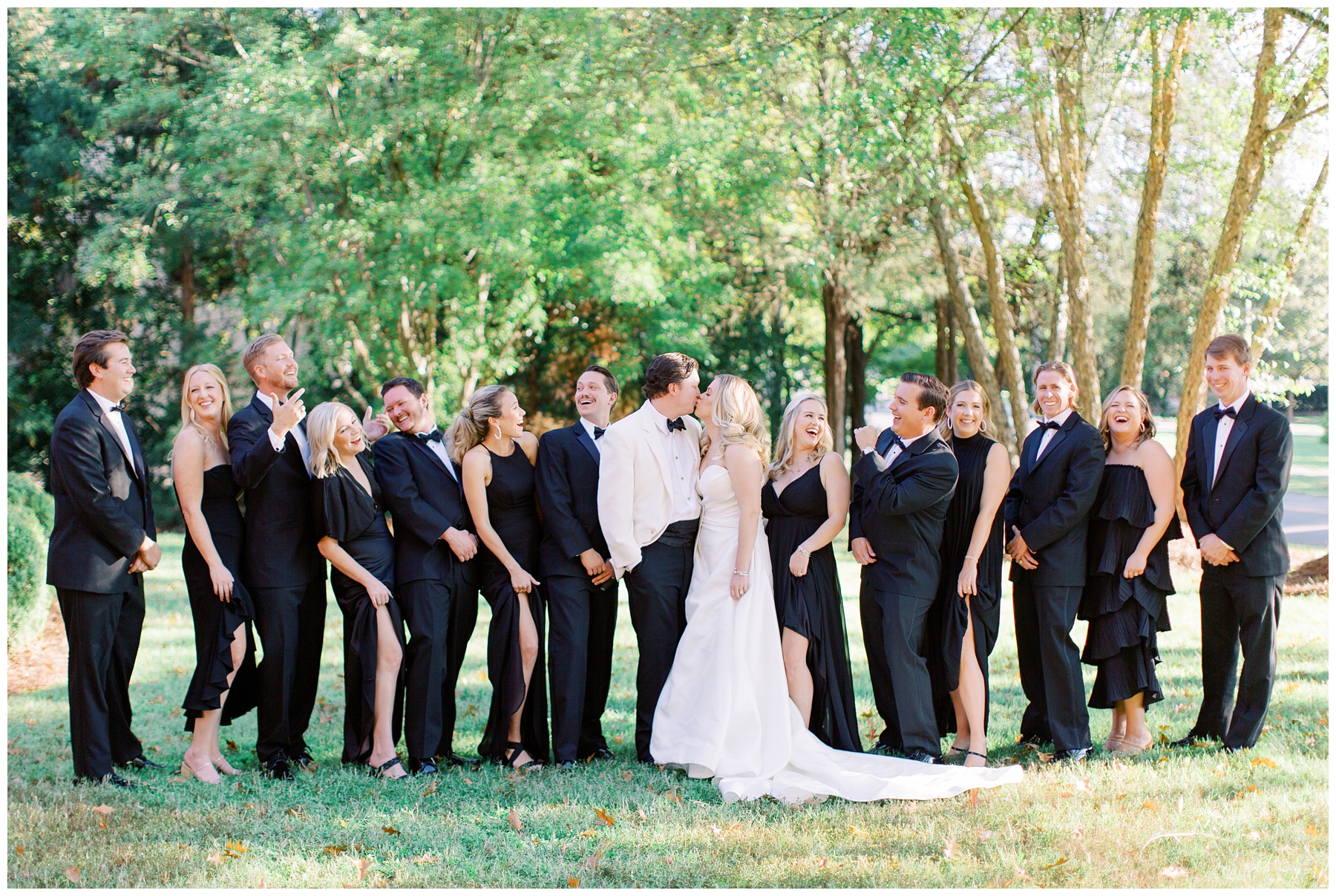 newlyweds kiss while wedding party laughs