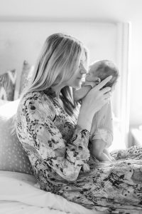 mother holds baby to nose during newborn photos at home