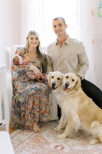 parents sit with newborn and dogs