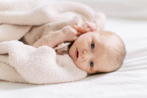 baby lays in blanket on bed during newborn photos at home
