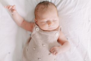 baby sleeps in tan jumper during Charlotte newborn session