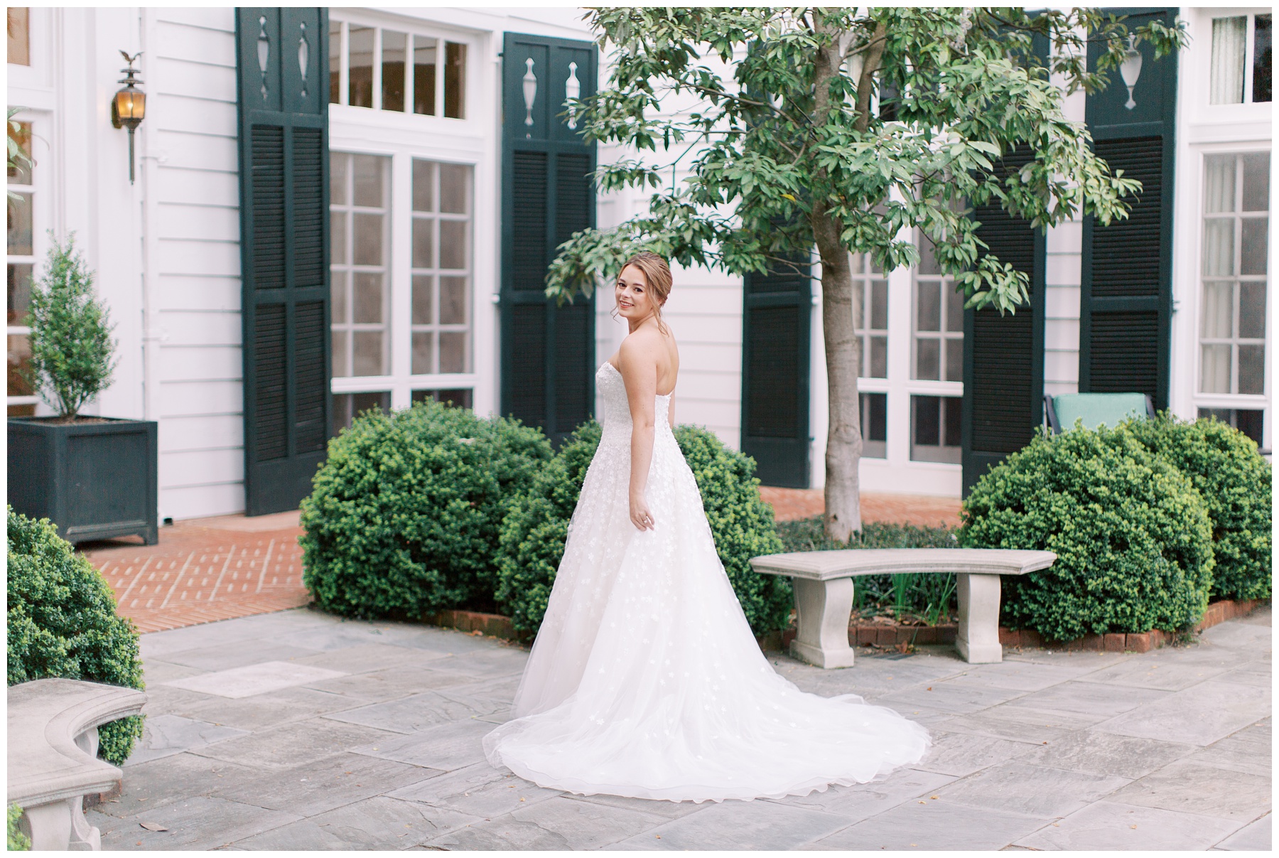 bride stands looking over shoulder on patio at the Duke Mansion in Charlotte NC