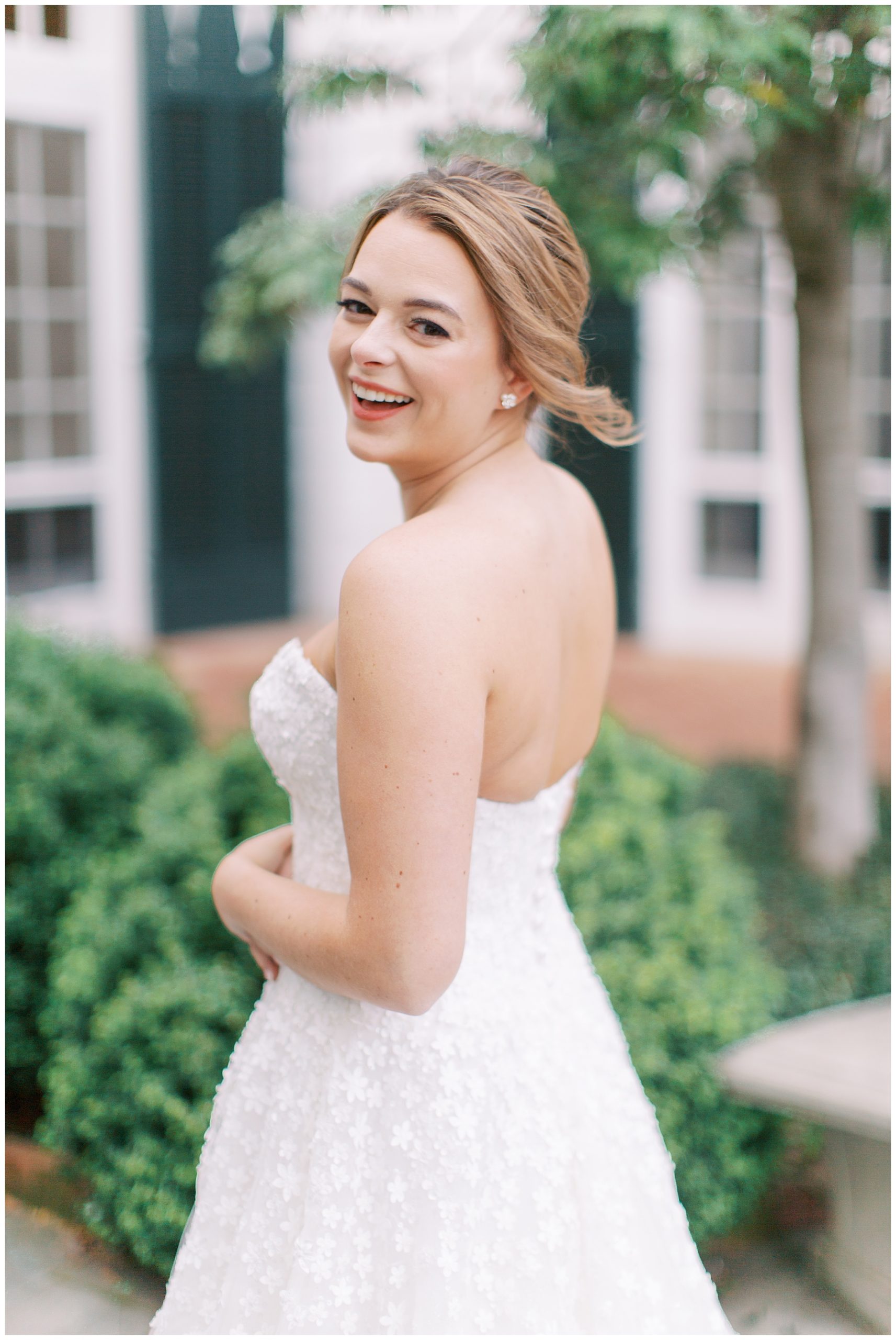 bride laughs over shoulder with updo in strapless gown during Duke Mansion bridal portraits