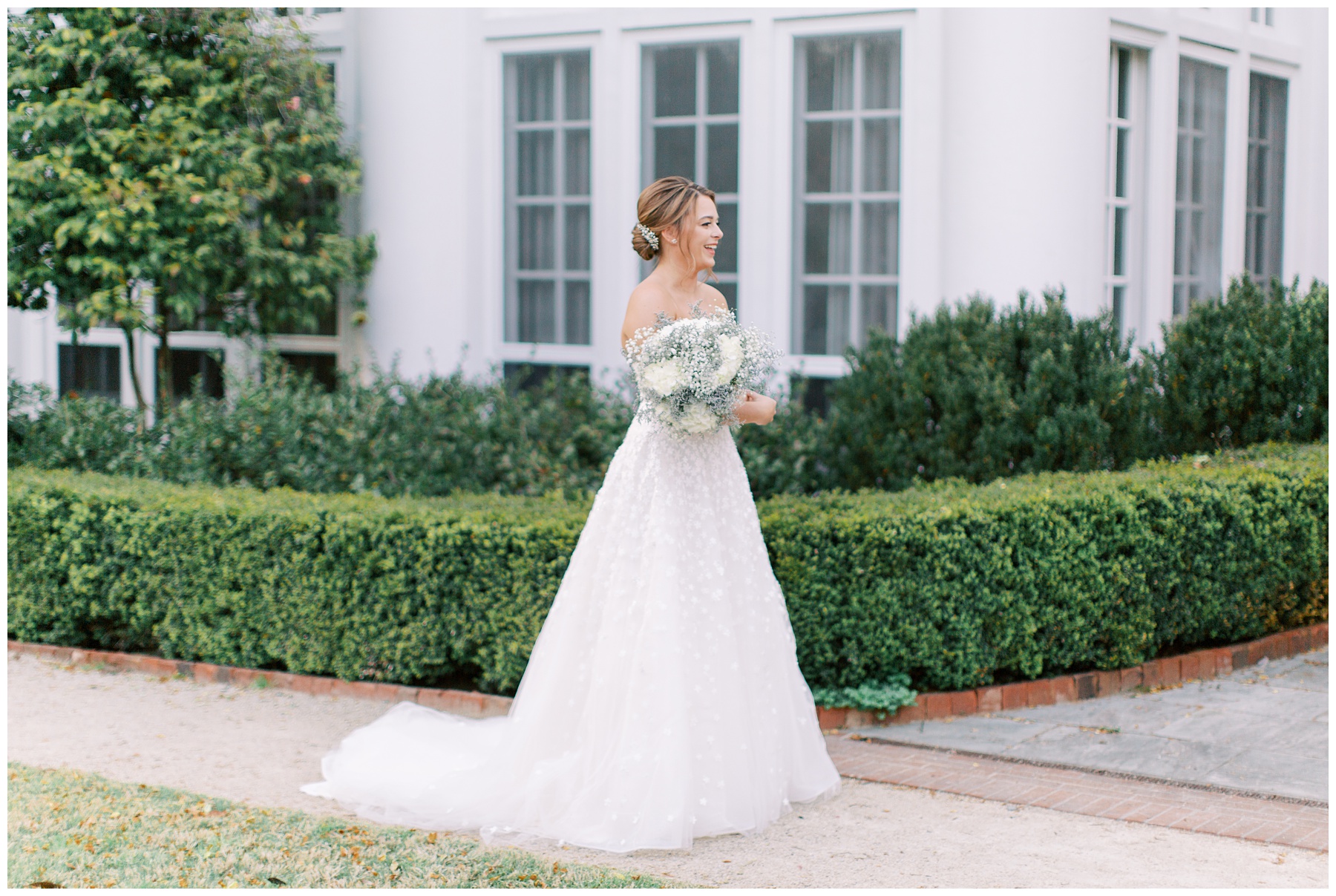 bride walks with bouquet of white flowers and baby's breath outside Duke Mansion 