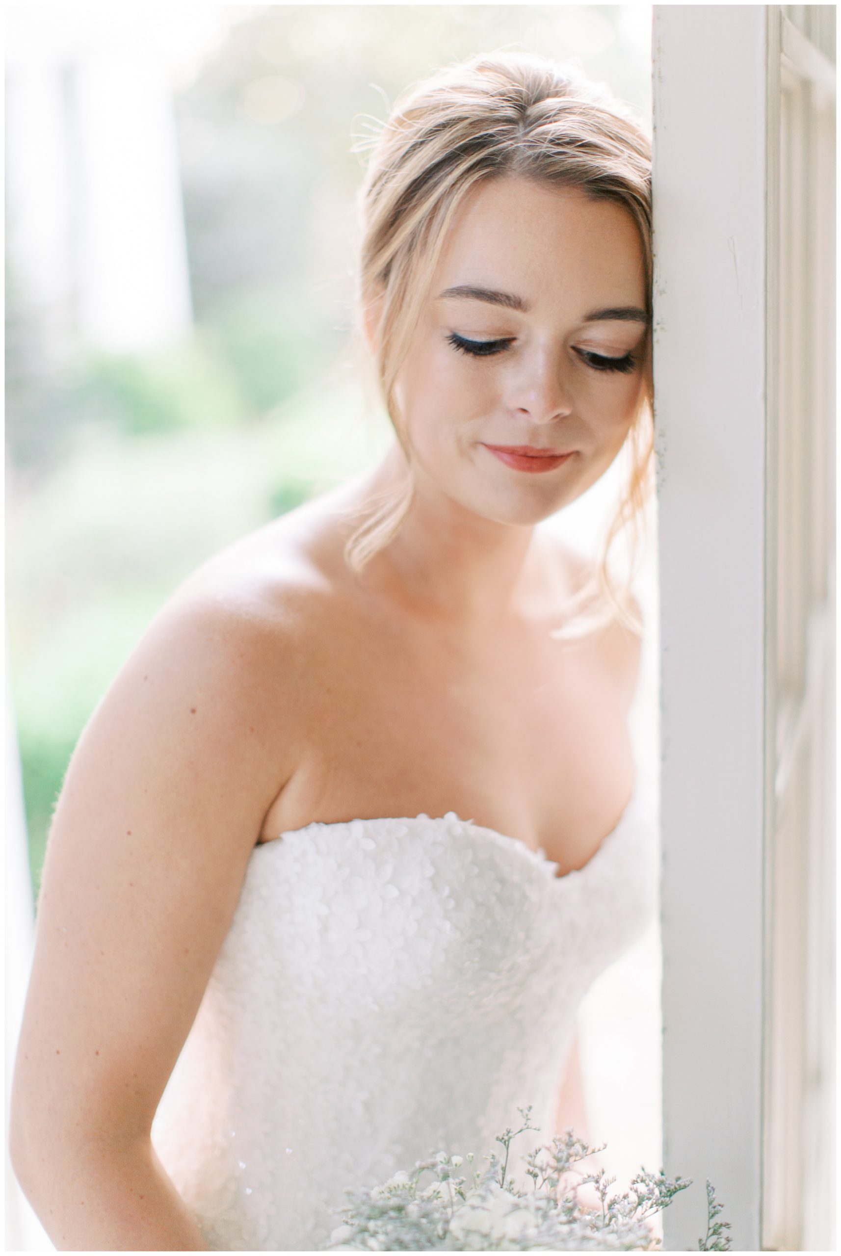 bride leans against doorway in strapless wedding gown