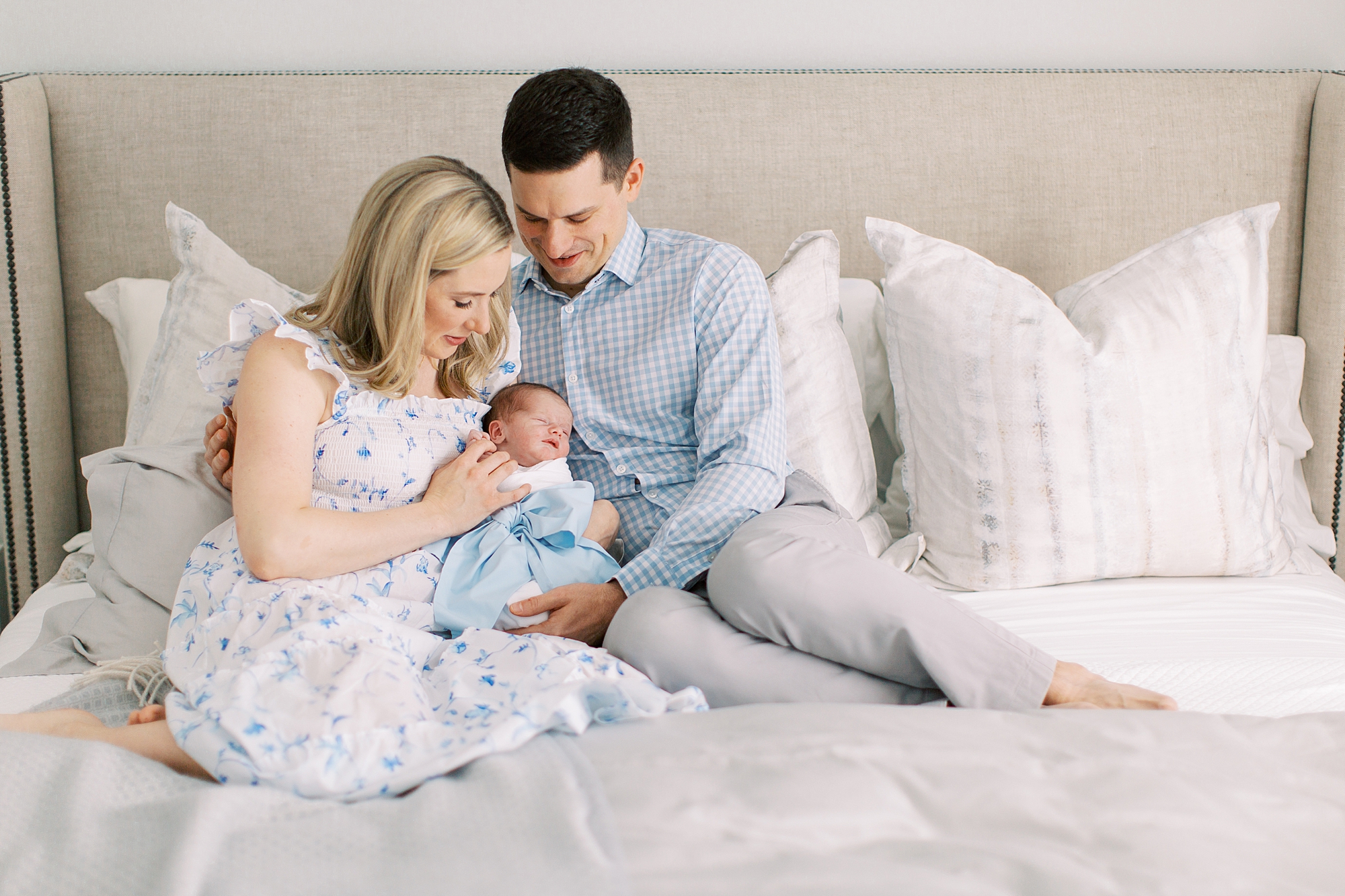 new family sits on bed holding baby boy during lifestyle newborn session