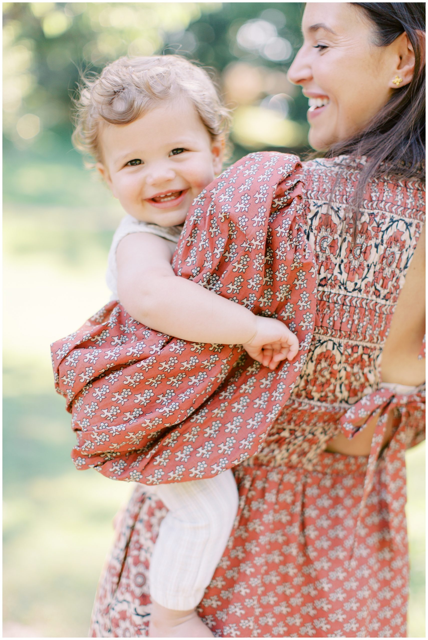 mom stands with toddler on her hip during family session in Charlotte NC at Latta Park