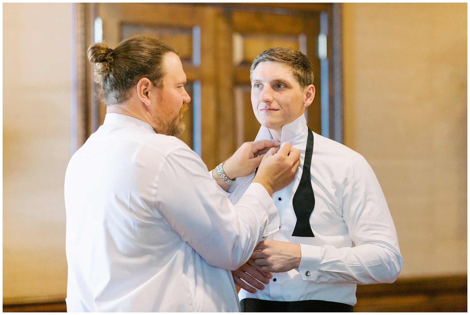groomsman helps groom with bowtie before Charlotte wedding