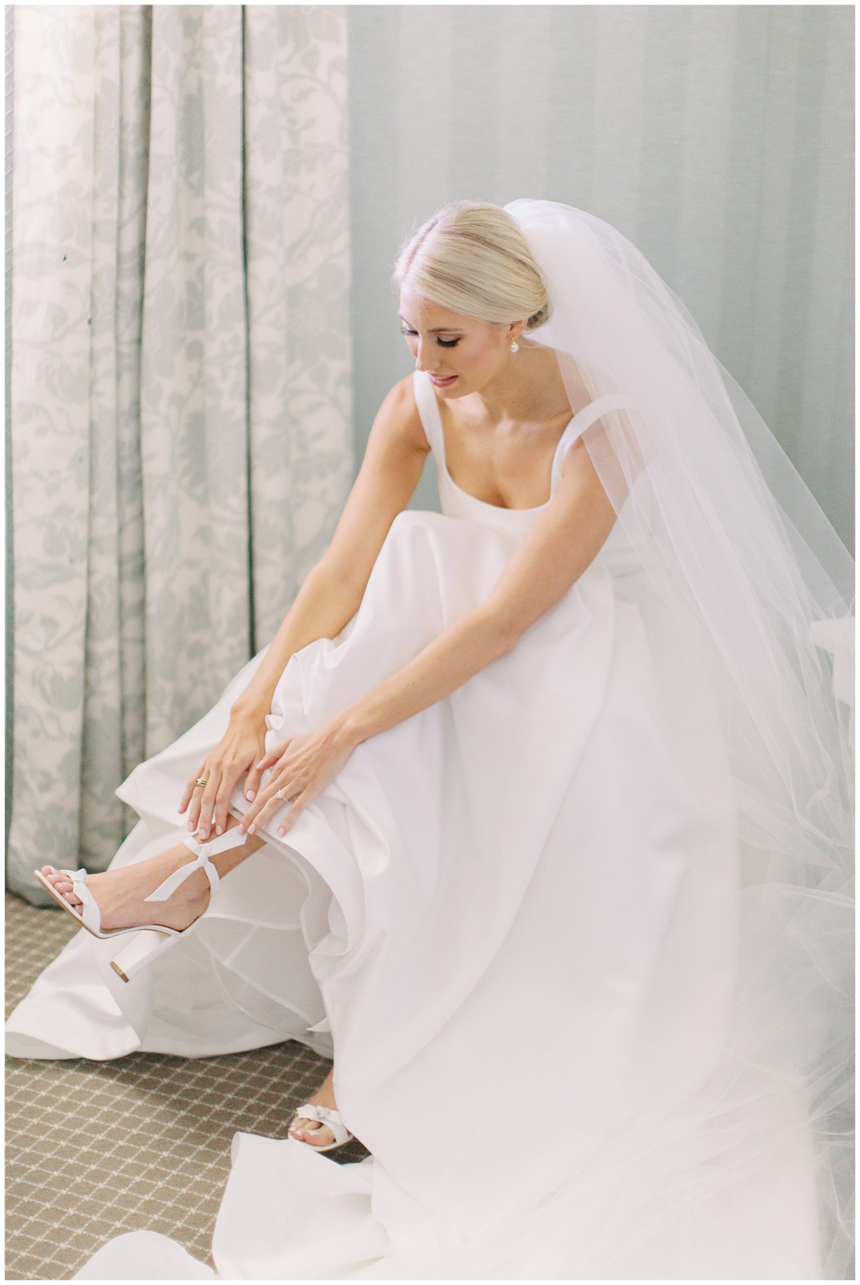 bride ties ribbon on shoes during prep for Charlotte NC wedding