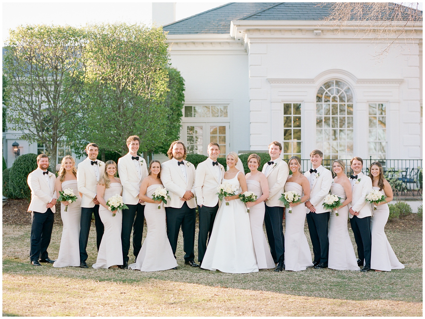 bride and groom stand with wedding party on lawn at Quail Hollow Club
