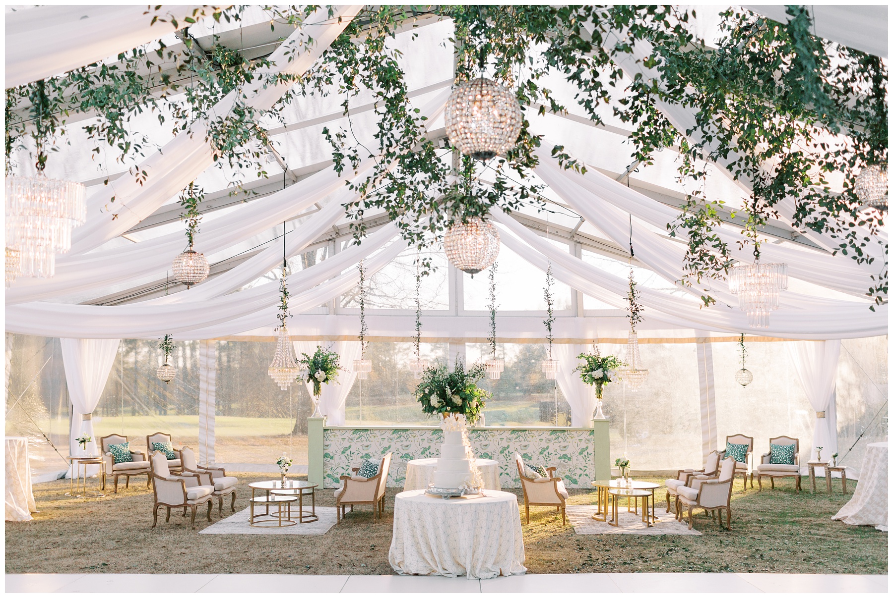 tented wedding reception seating area with hanging chandeliers and vines with custom bar with plant wallpaper at Quail Hollow Club